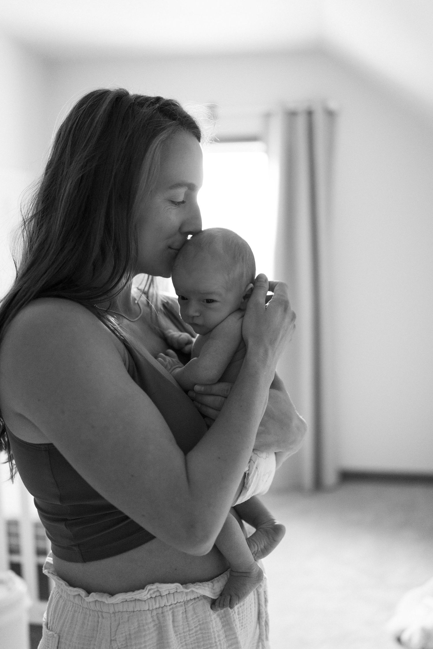 A tender black and white series of photos showing a mother lovingly embracing and cuddling with her baby.