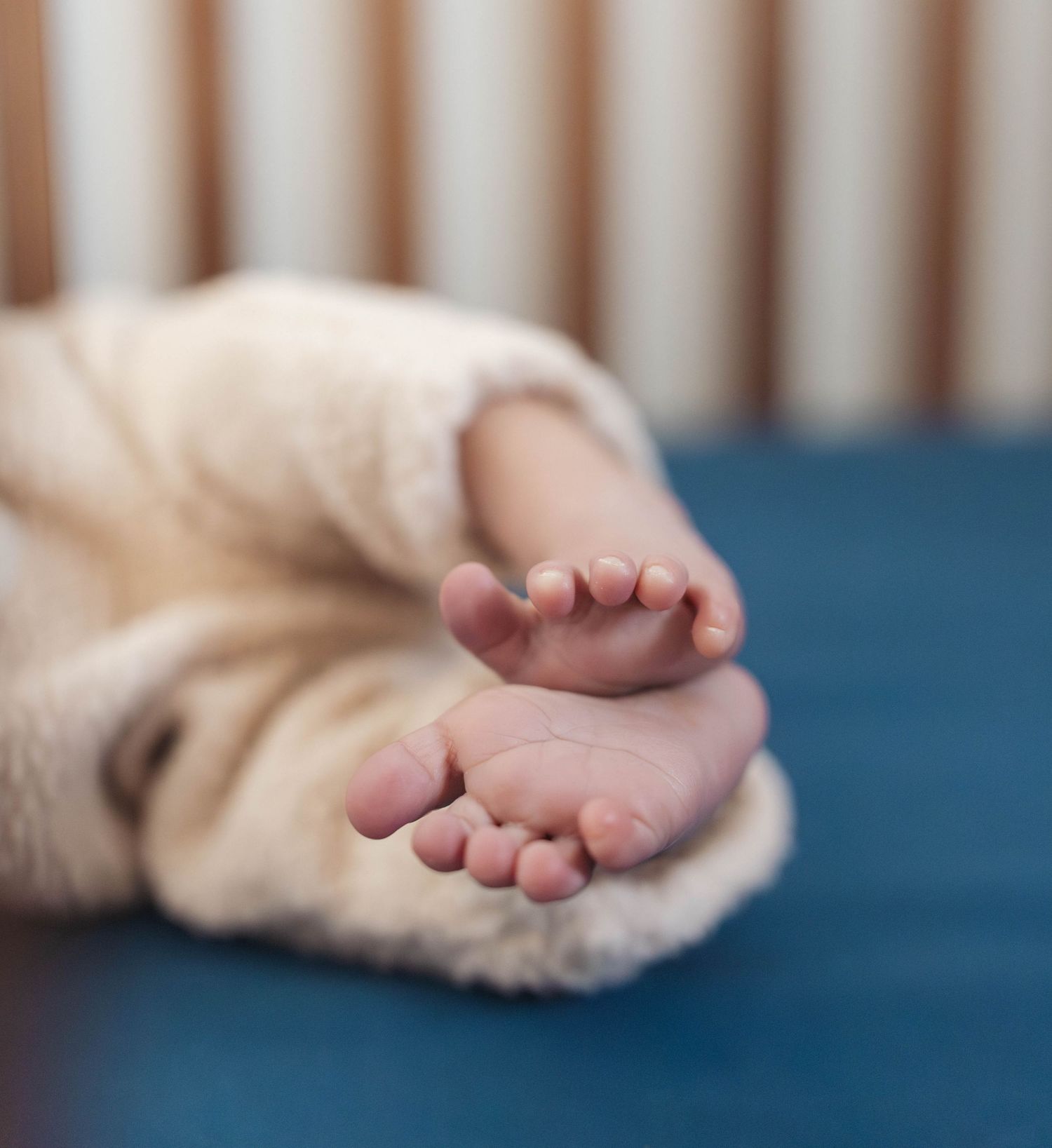 Close up view of tiny newborn baby feet against a soft blue background.