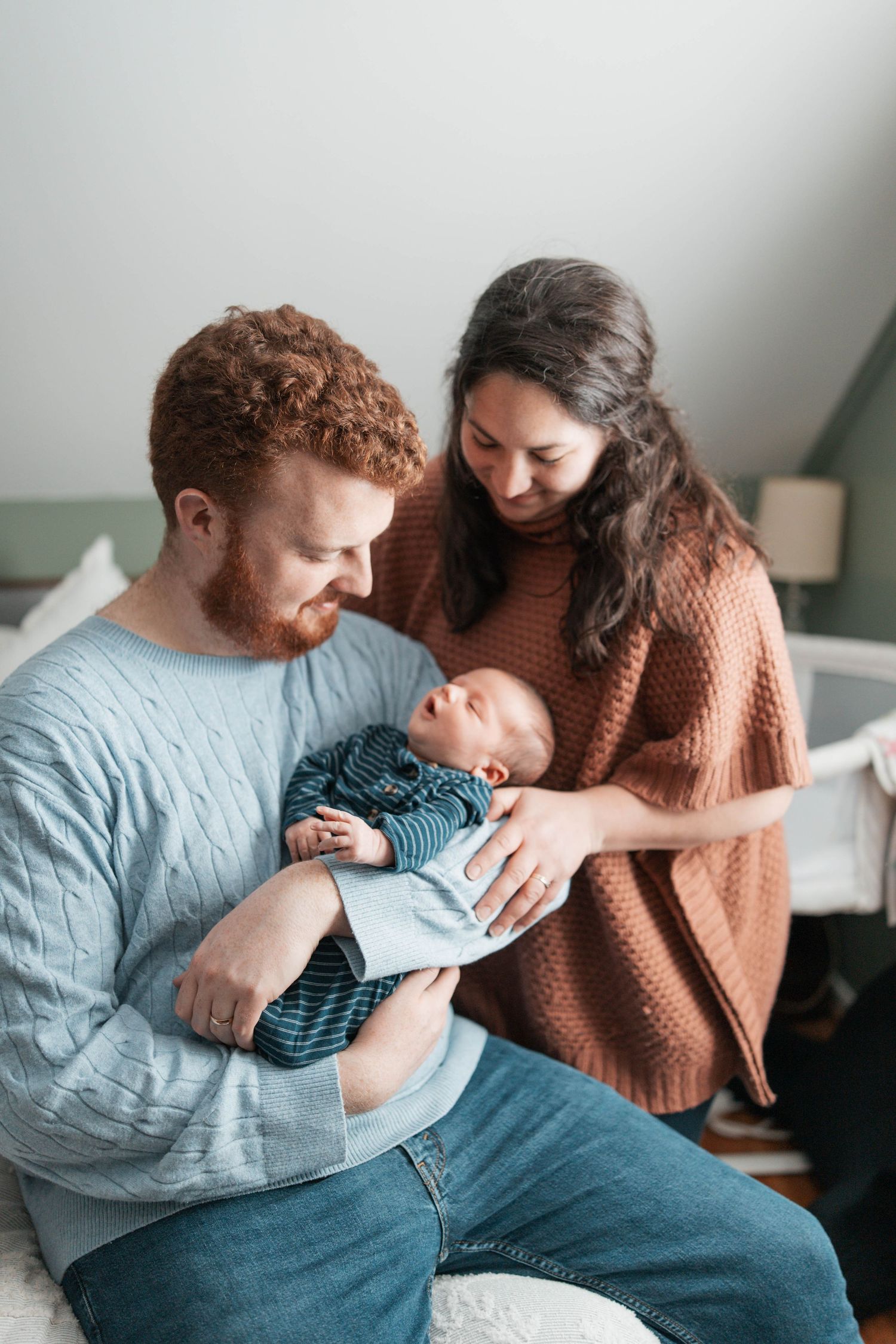 Parents share an intimate moment with their newborn baby while sitting together in a cozy room.