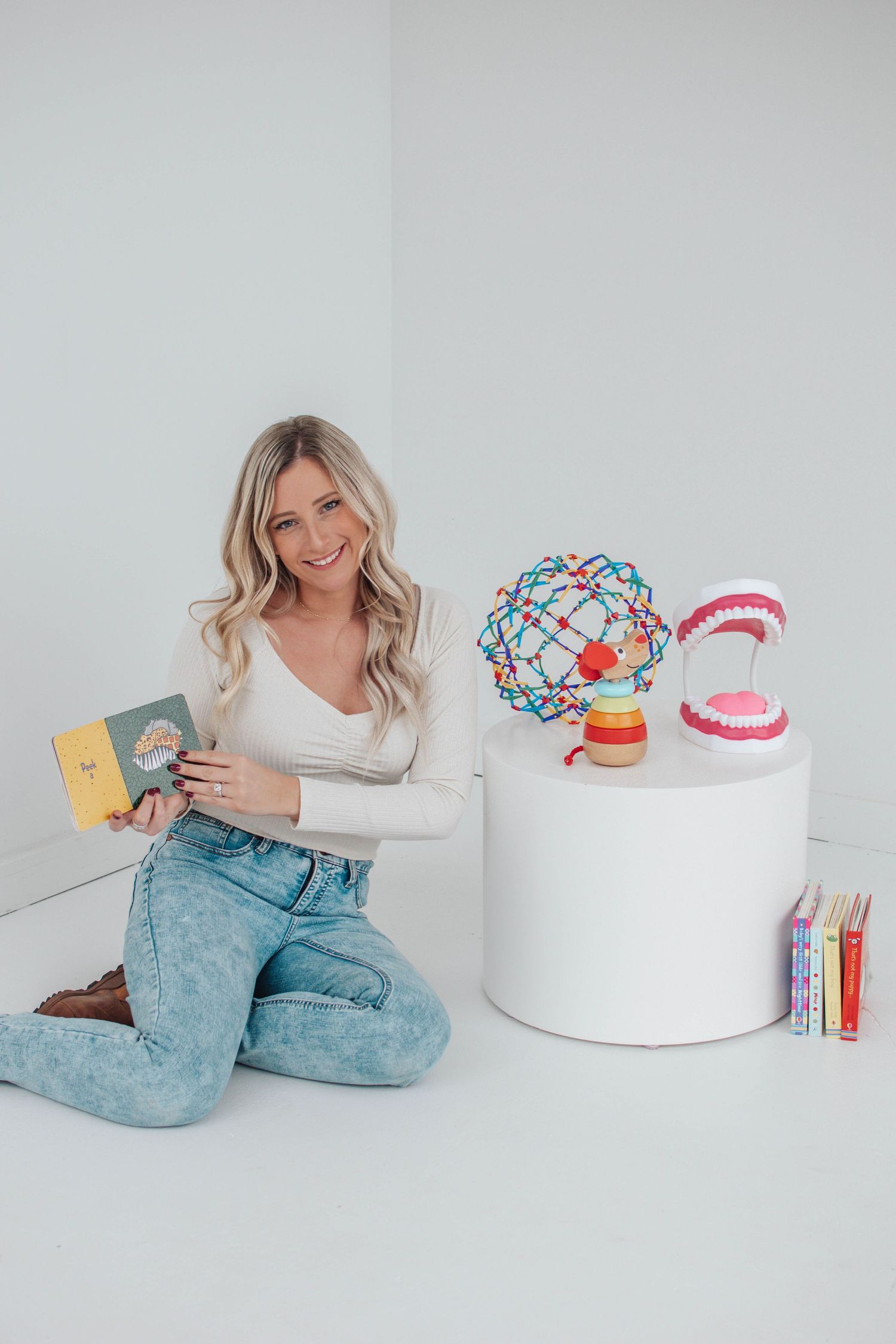 A lifestyle photo with educational props including books, colorful molecular models, and dental teaching aids on a white display.