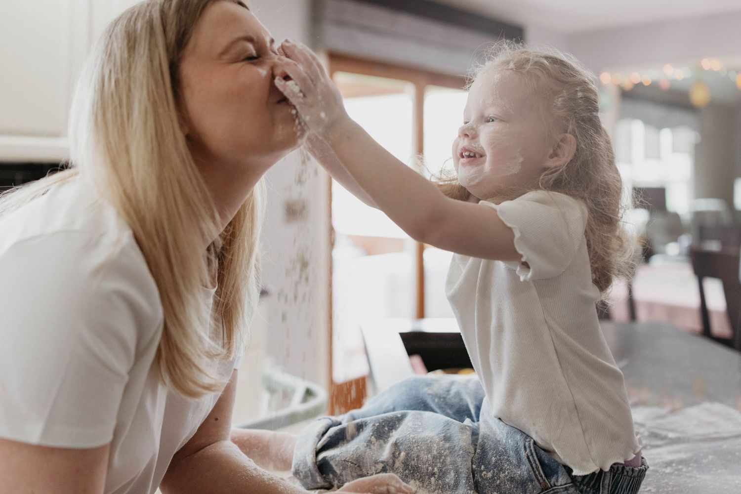 A joyful playful moment between parent and child sharing laughter while sitting on a bed.