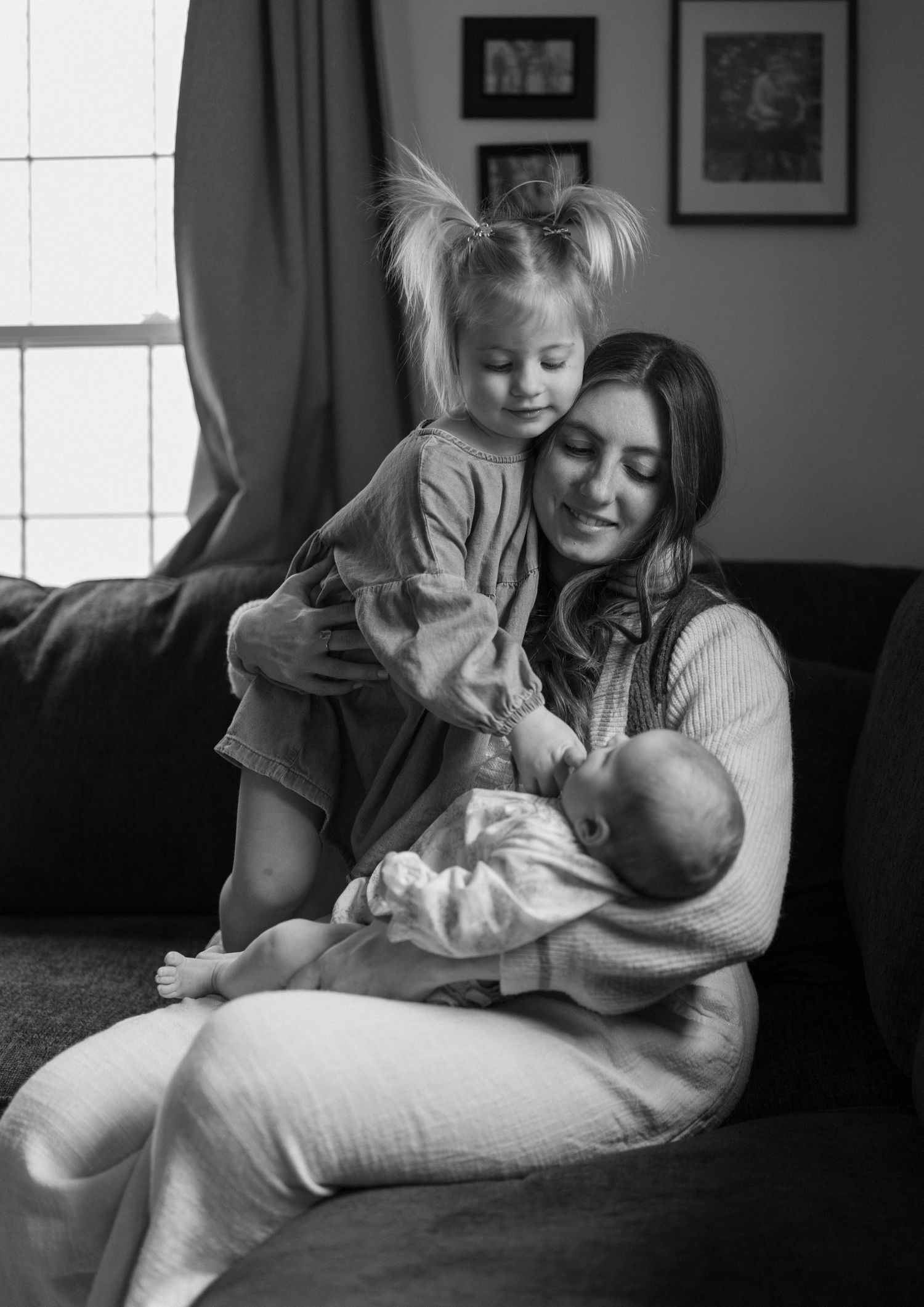 A tender black and white portrait of a family moment at home showing affectionate interaction between siblings and parent.