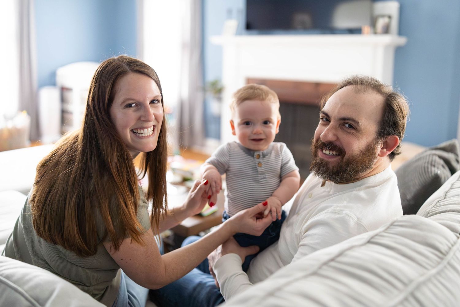 Happy family sitting together on couch at home with young child in playful domestic scene.