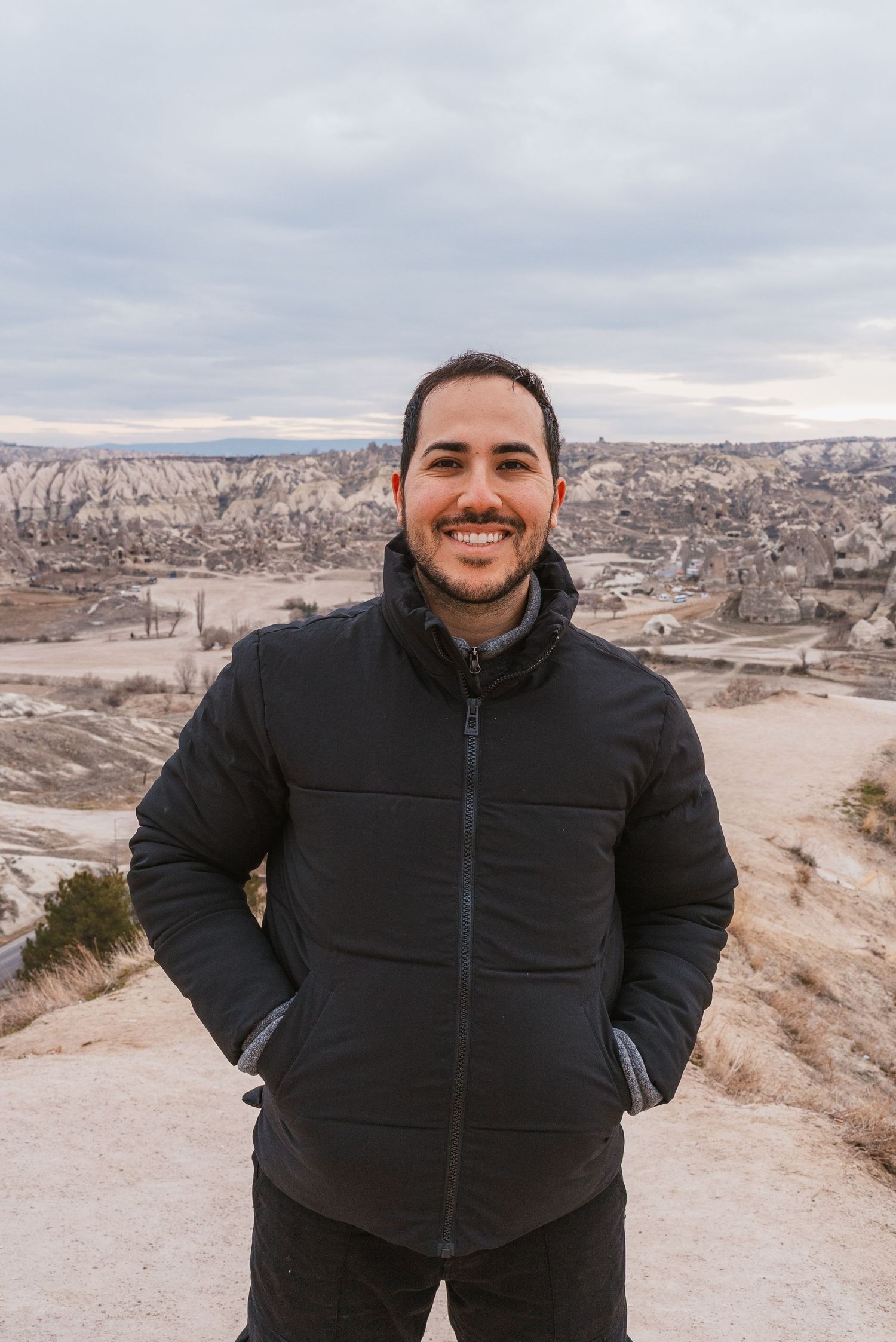 Person in a black winter jacket standing on a scenic overlook of Cappadocia, Turkey.