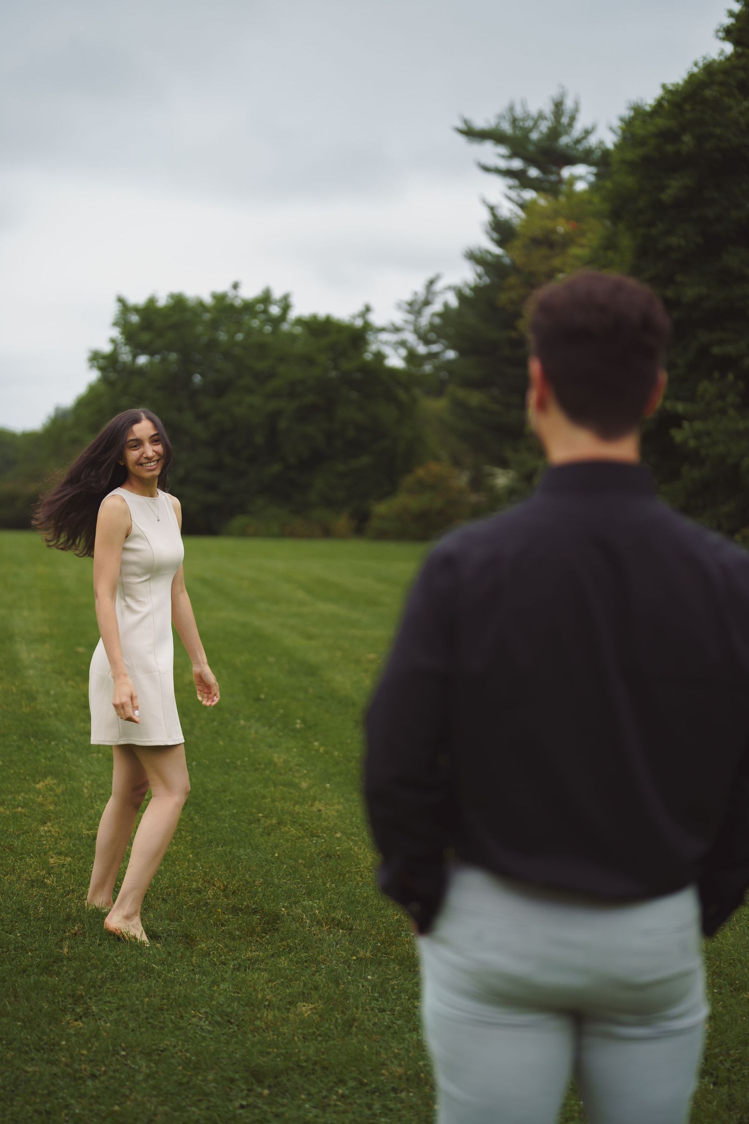 Four sequential shots showing someone in white running and jumping joyfully across a grassy field on a summer day.
