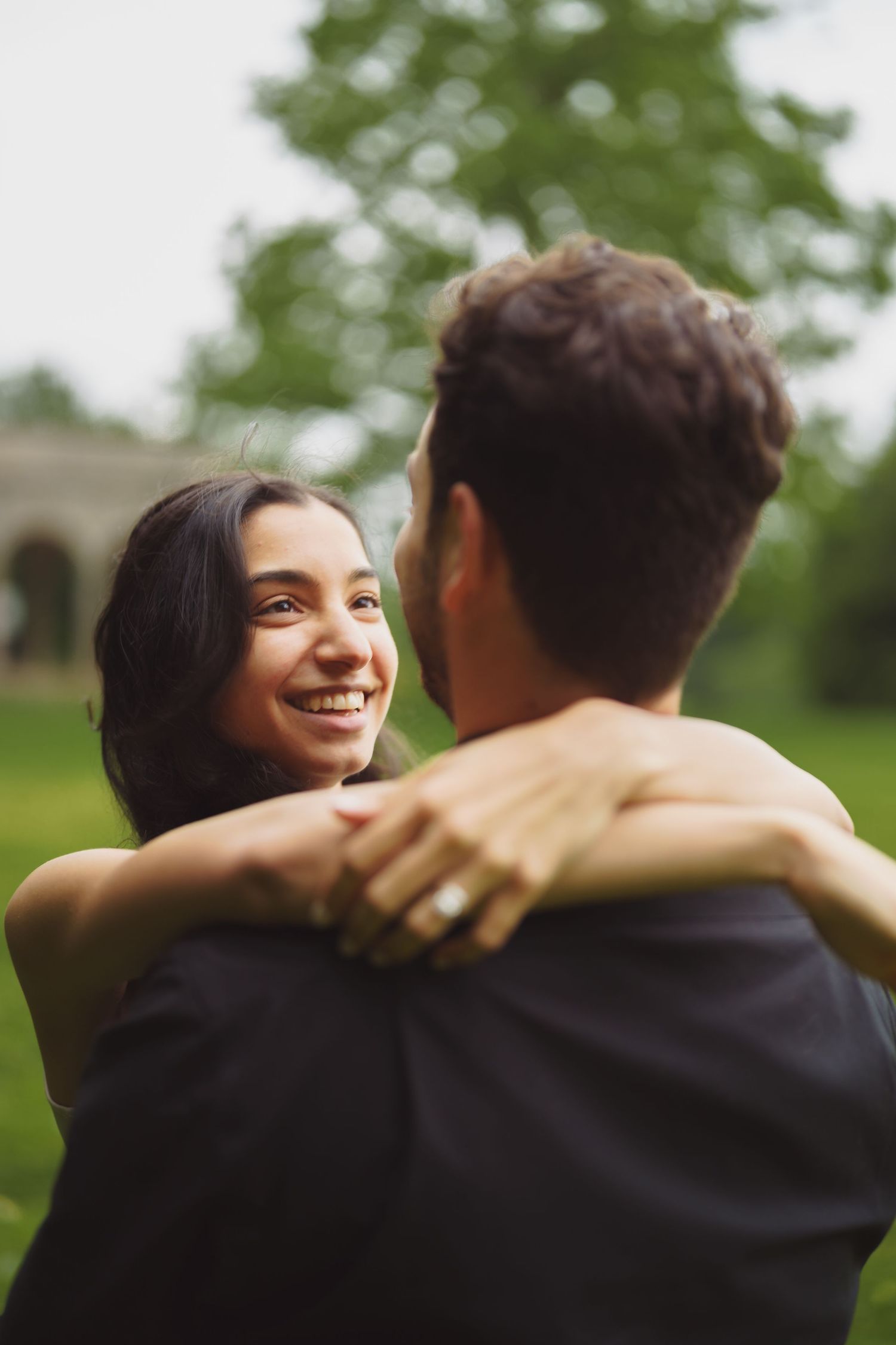 A romantic couple embracing outdoors while sharing a joyful moment in a green garden setting.