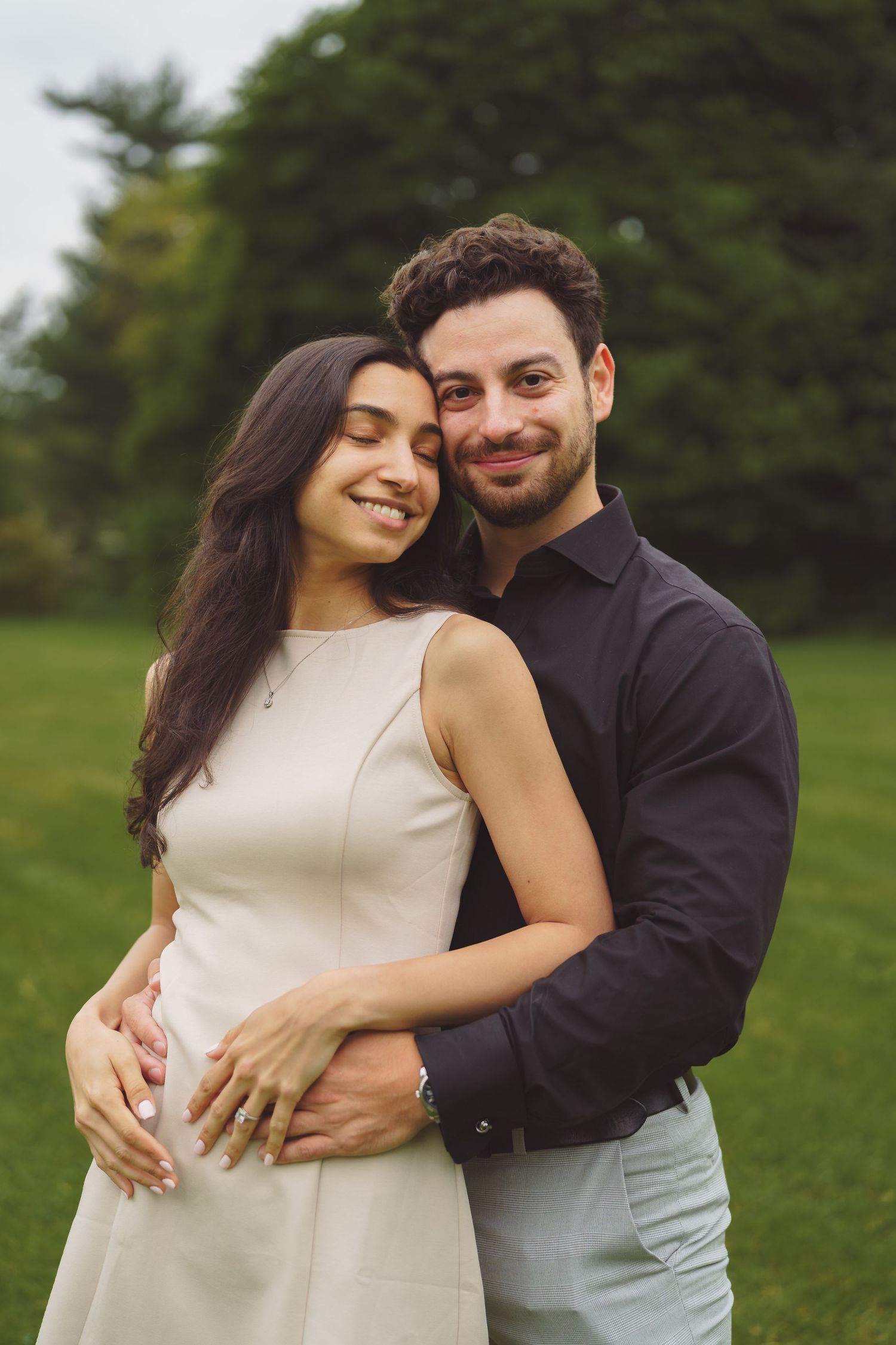 A romantic couple embraces while sharing intimate moments in a grassy outdoor setting.
