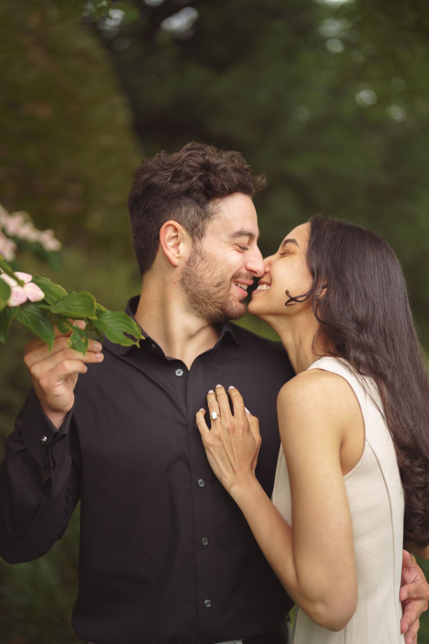 A tender moment between a couple sharing kisses and smiles in an outdoor garden setting.
