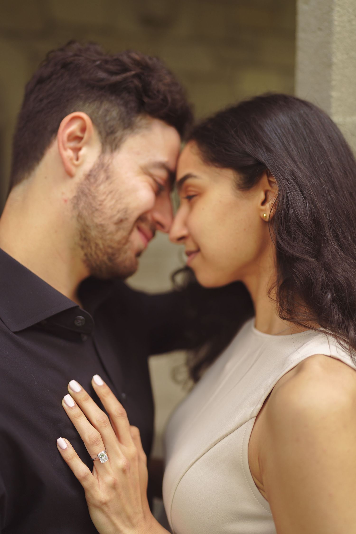 An intimate sequence of a couple in black and beige sharing romantic moments against a light colored wall.