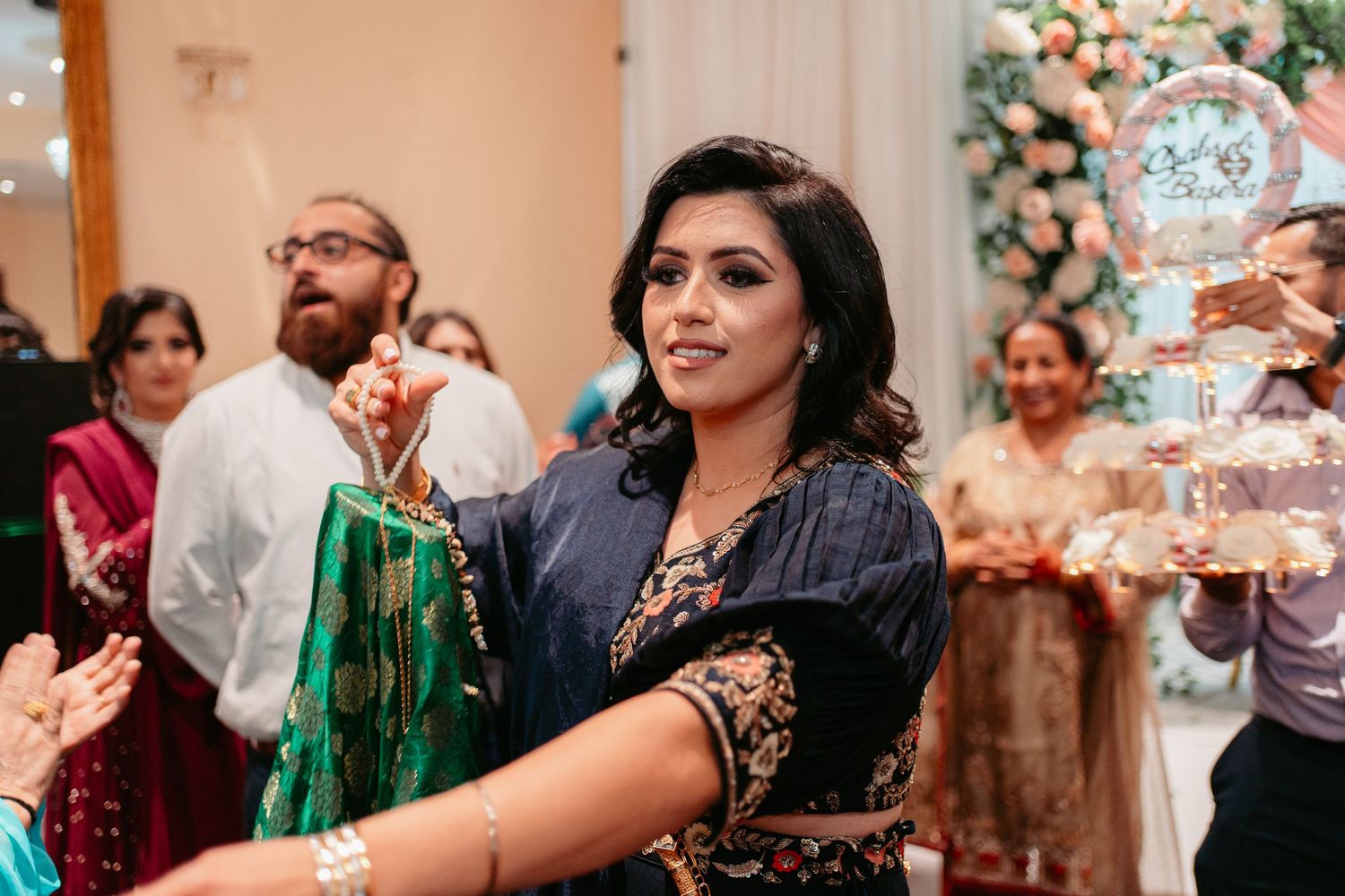 Guests celebrate at an indoor party with elegant decorations and a champagne tower display in the background.