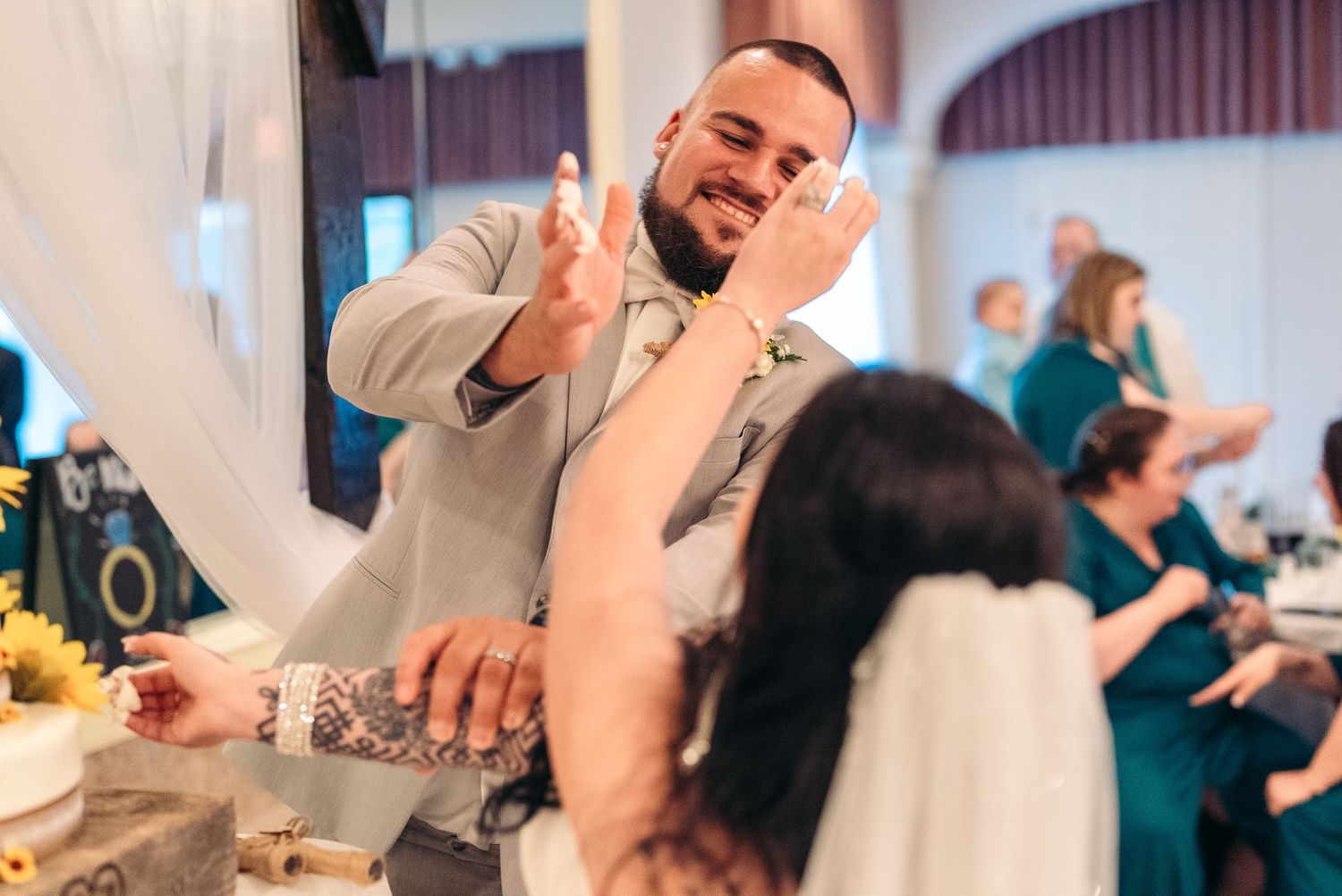A smiling person in formal attire serves and interacts with guests at an elegant indoor event celebration.