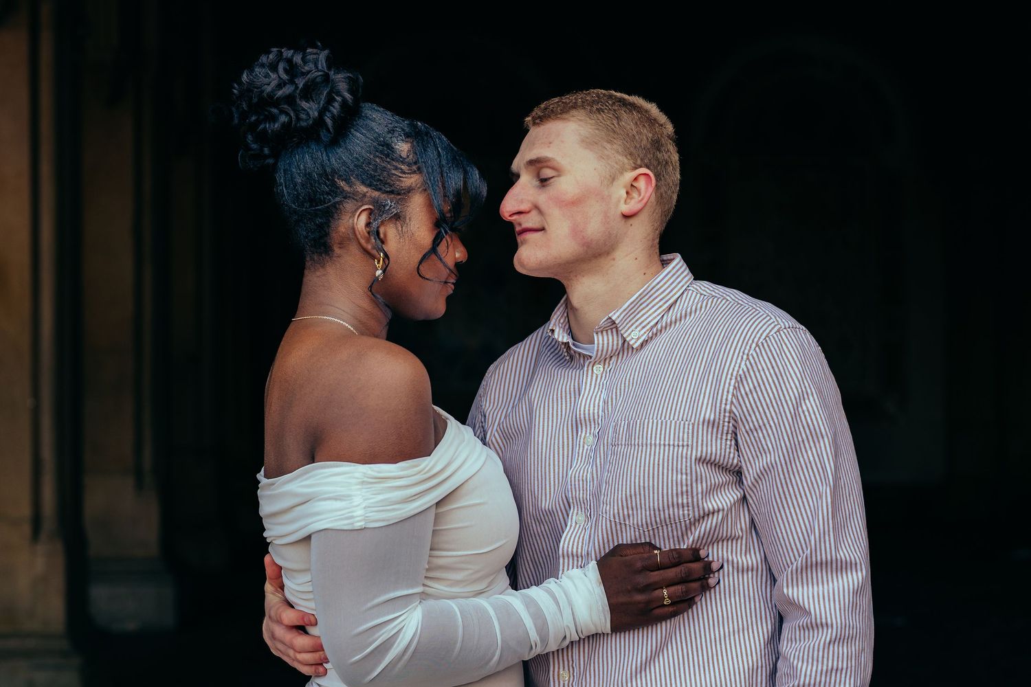 A couple in semi-formal attire embraces intimately while sharing a romantic moment together during a photo session.