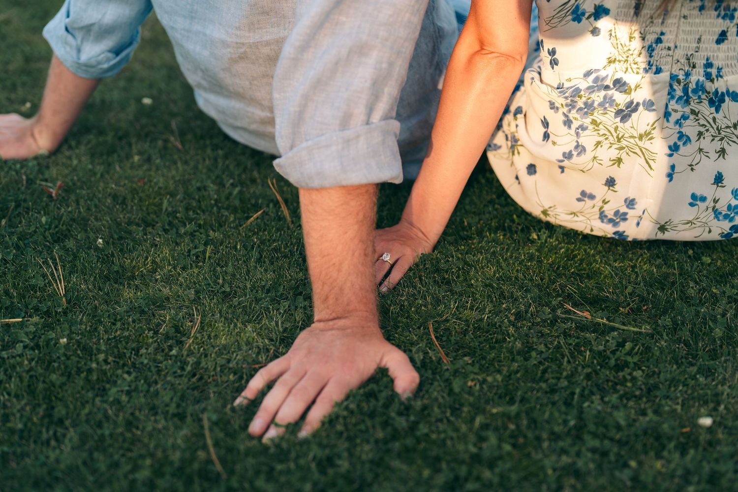 A hand rests on green grass beside casual summer clothing in an outdoor setting.