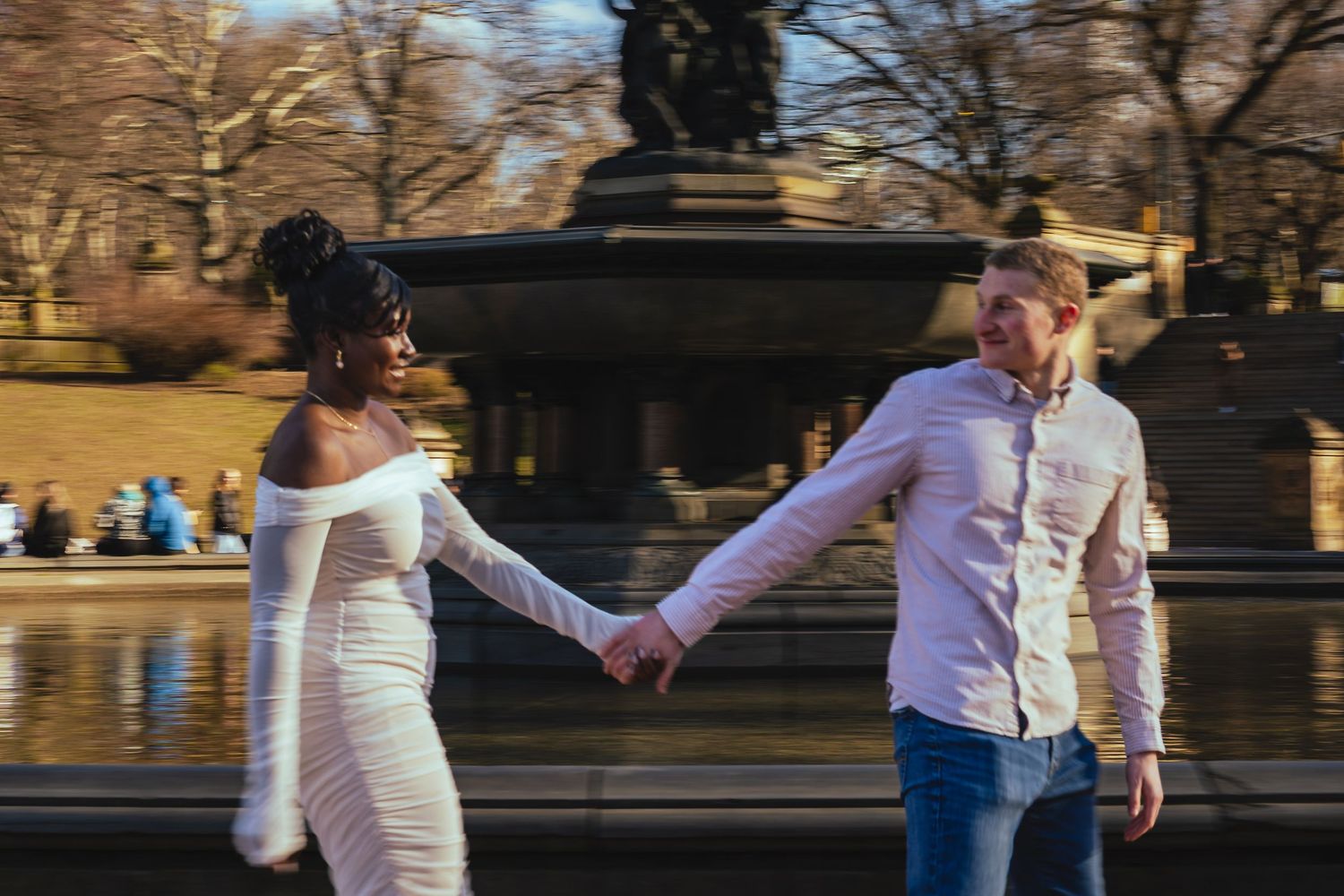 A couple holds hands while walking past the Bethesda Fountain in Central Park on a winter afternoon.