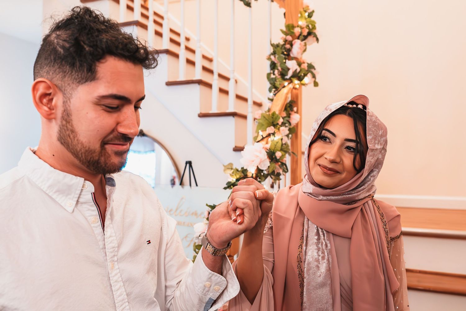 A couple shares a tender moment on a staircase adorned with floral decorations.