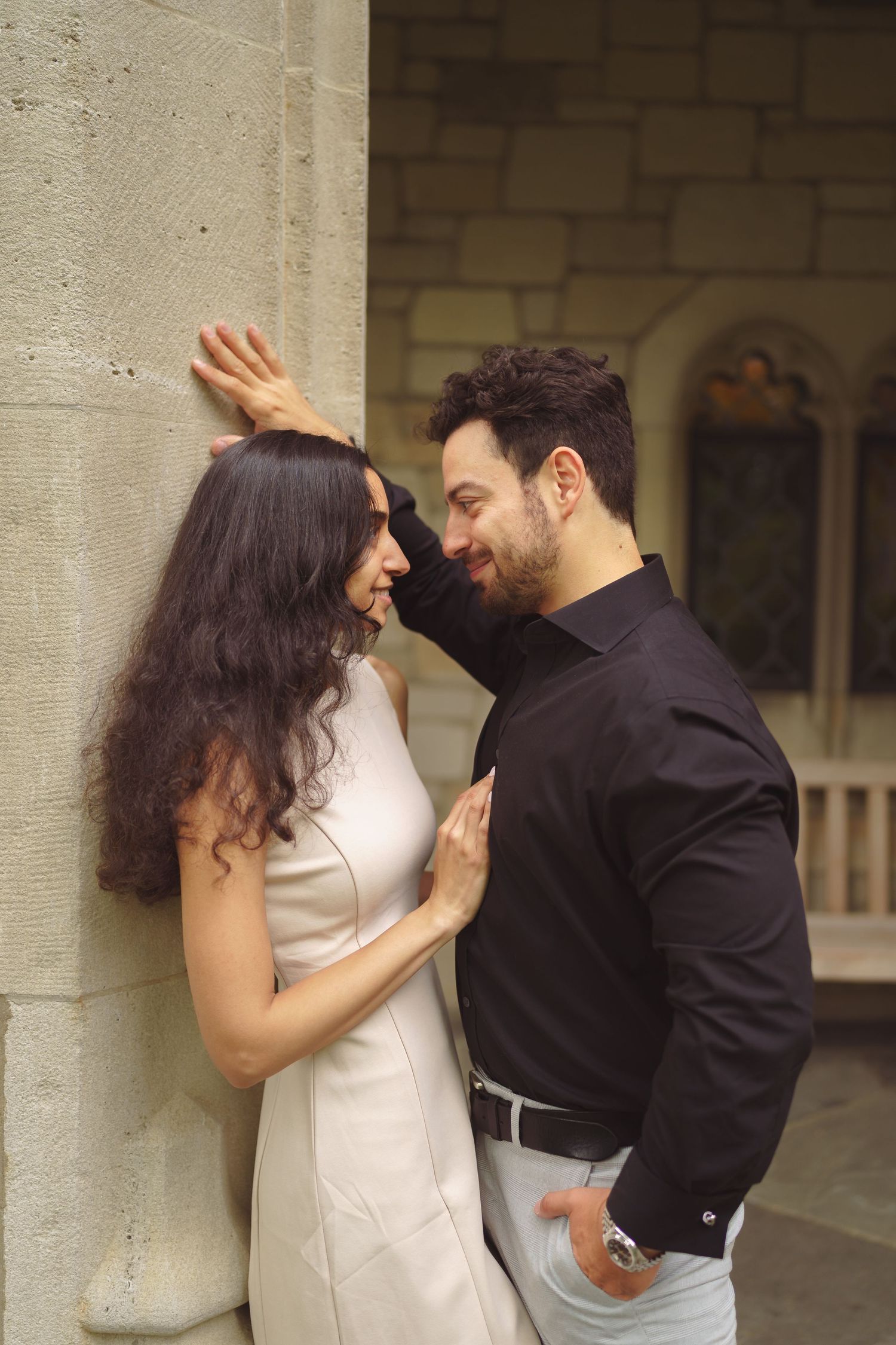 A couple shares tender moments while dancing together against a stone wall backdrop.