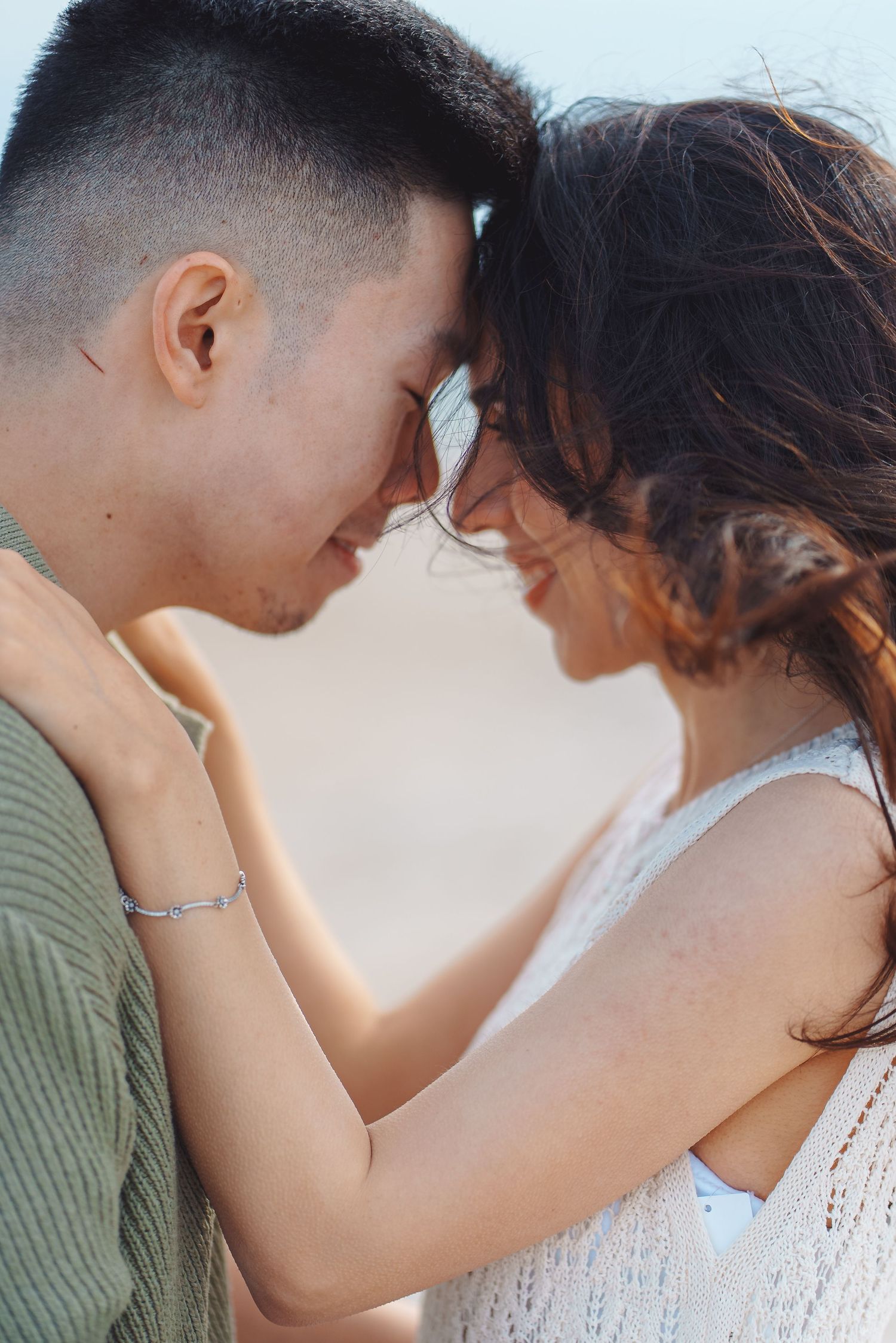 A romantic couple shares an intimate moment touching foreheads against soft lighting in a tender embrace.