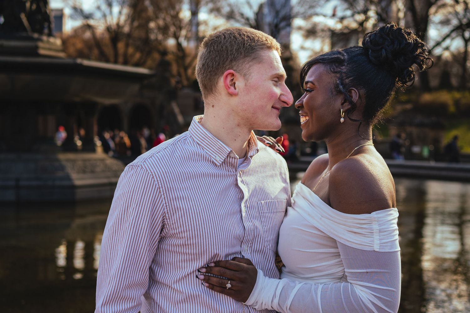 A romantic couple shares an intimate moment near the pond at sunset in Central Park, New York.