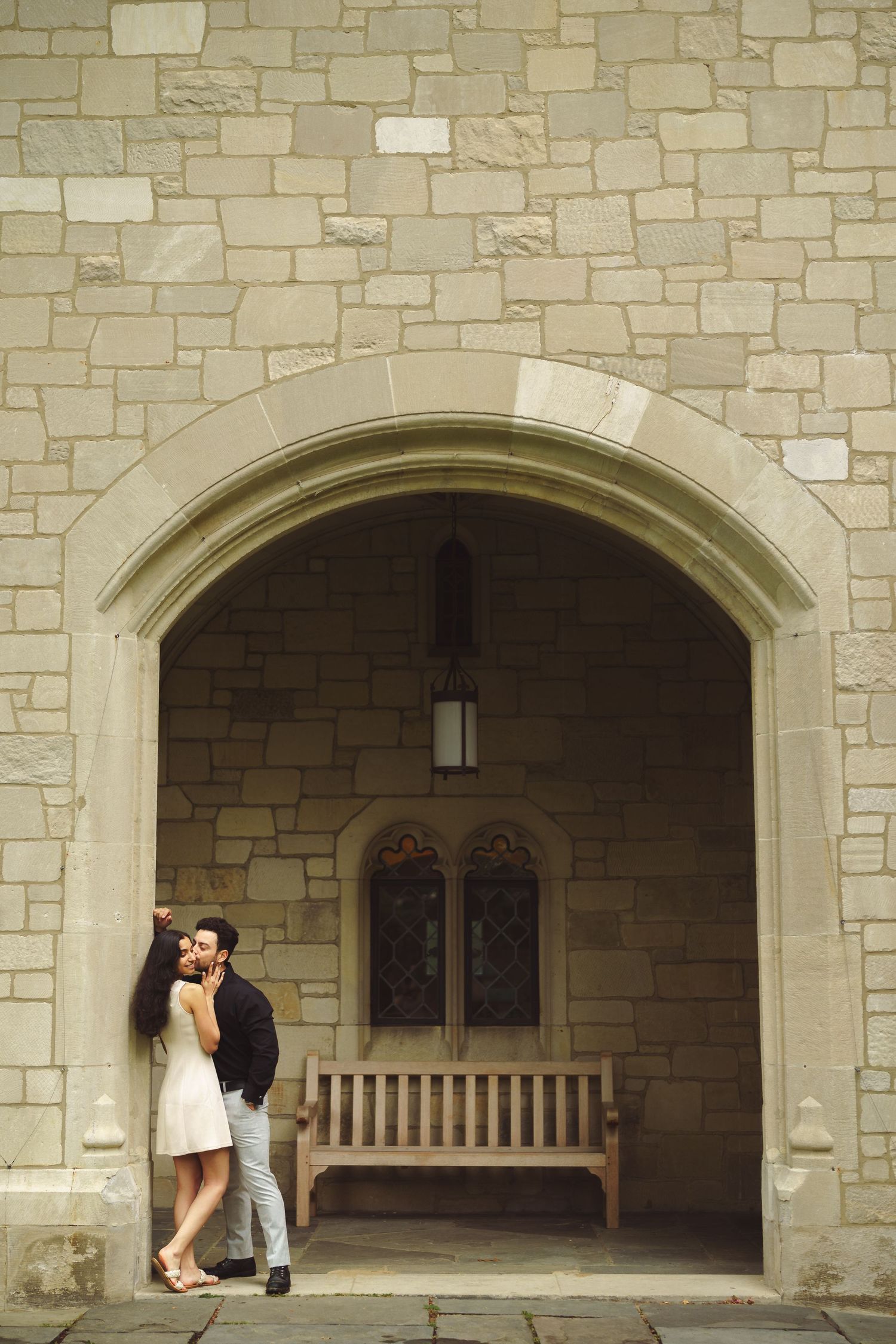 A series of photos showing a romantic moment under stone archways with a wooden bench visible.