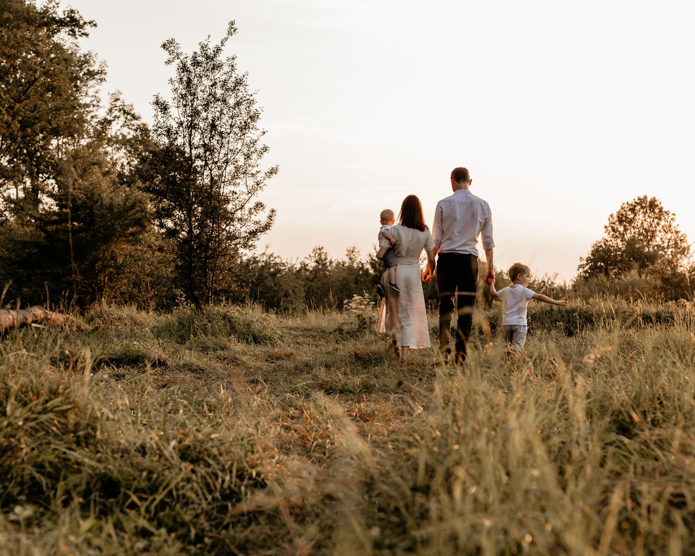 Group walking together through a golden sunlit meadow at sunset with trees in the background. Seoul