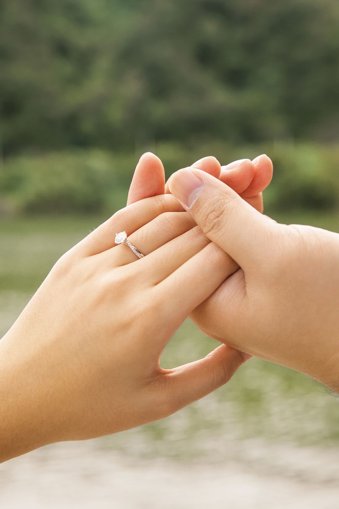 Close-up sequence of hands linking pinky fingers together in a pinky promise gesture against a blurred outdoor background.
