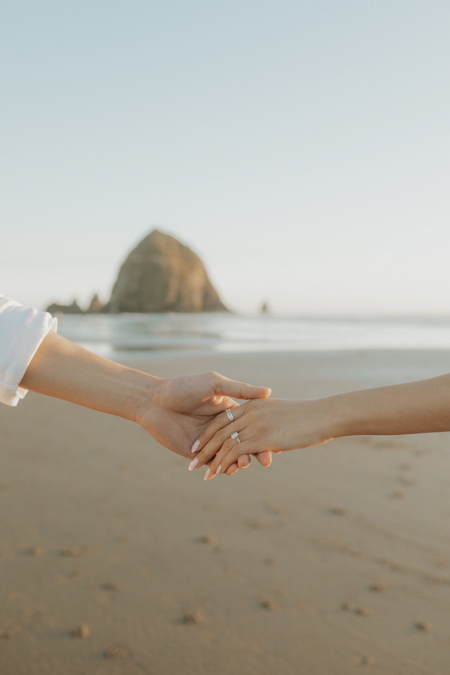 A series of four images showing hands reaching and holding each other against a soft, sandy beach backdrop.