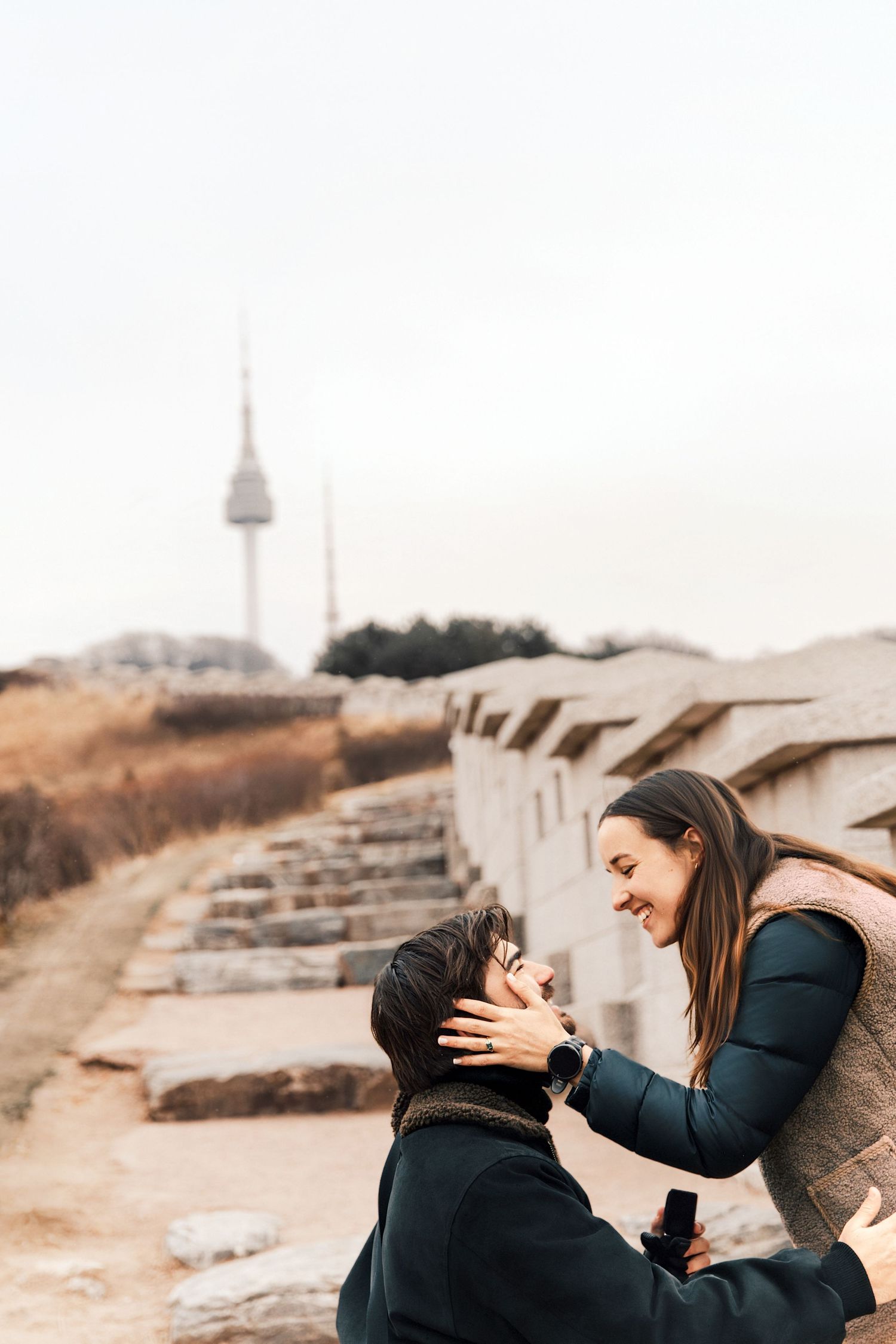 A couple shares intimate moments during a sunset engagement photoshoot on stone steps in a natural setting.