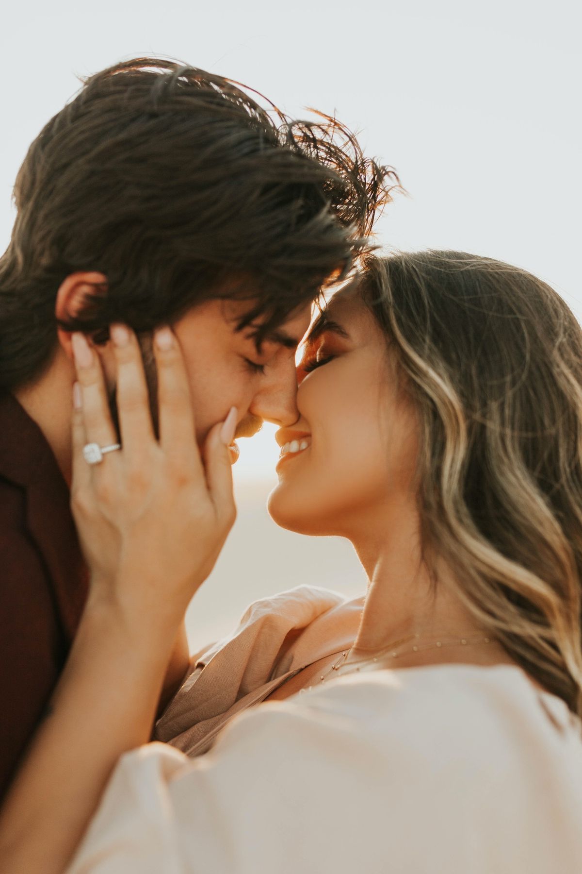 A romantic couple sharing an intimate moment at sunset with golden light illuminating their profiles.