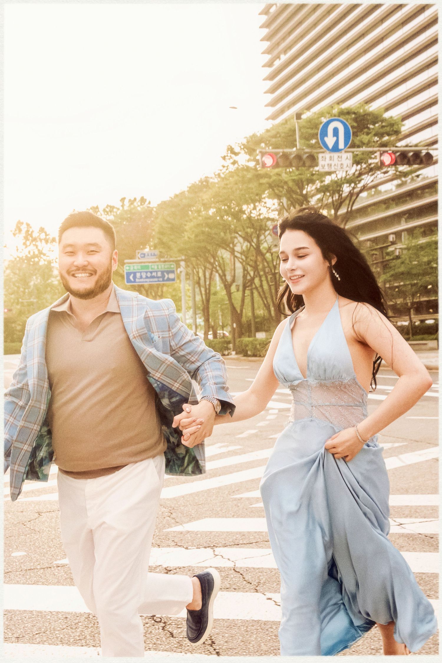A couple in casual attire shares playful moments while walking together on a sunny day outdoors. Engaged couple, proposal session with Nilo