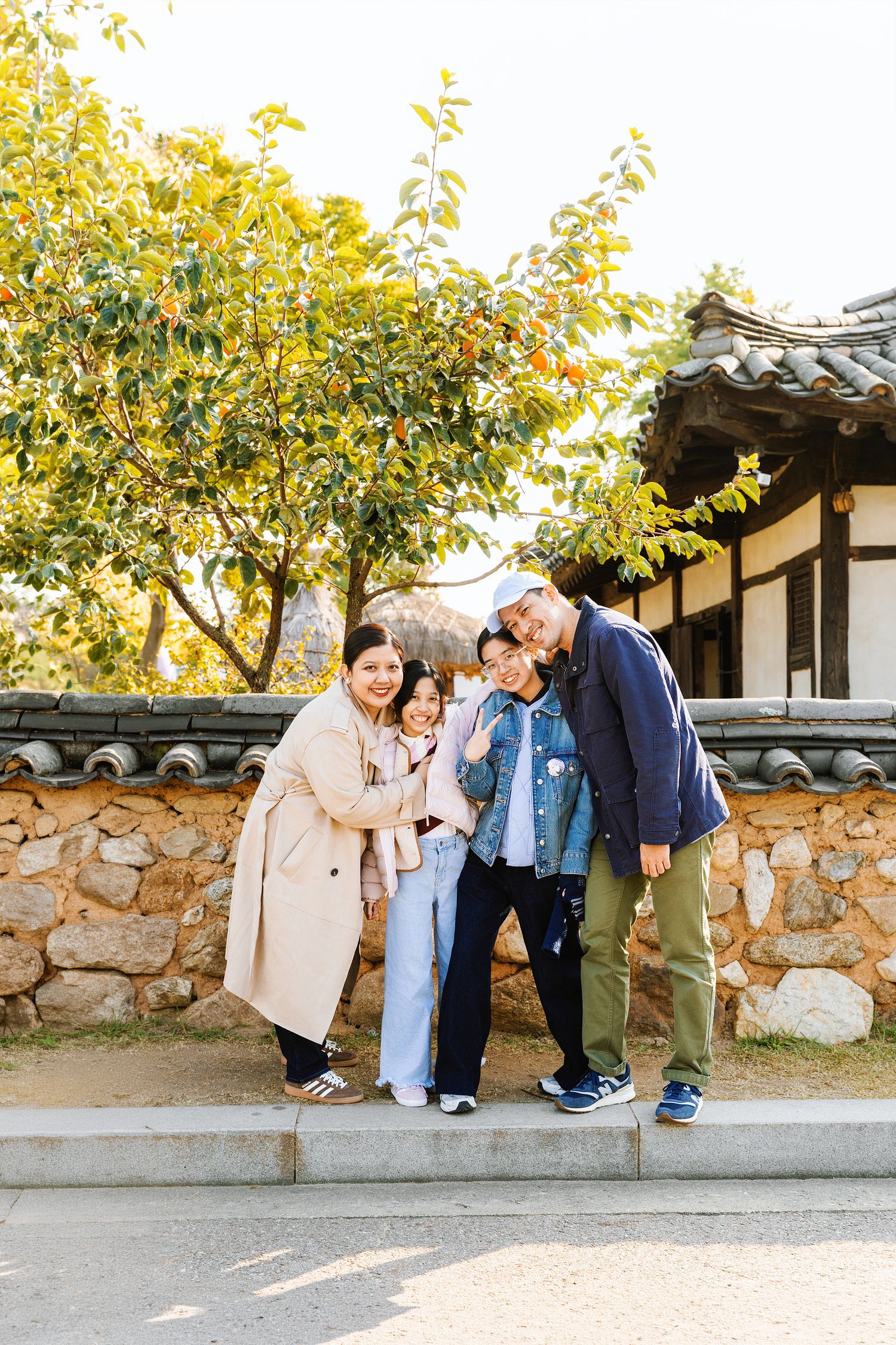 A group enjoying a playful moment together while walking along a traditional stone wall in autumn.