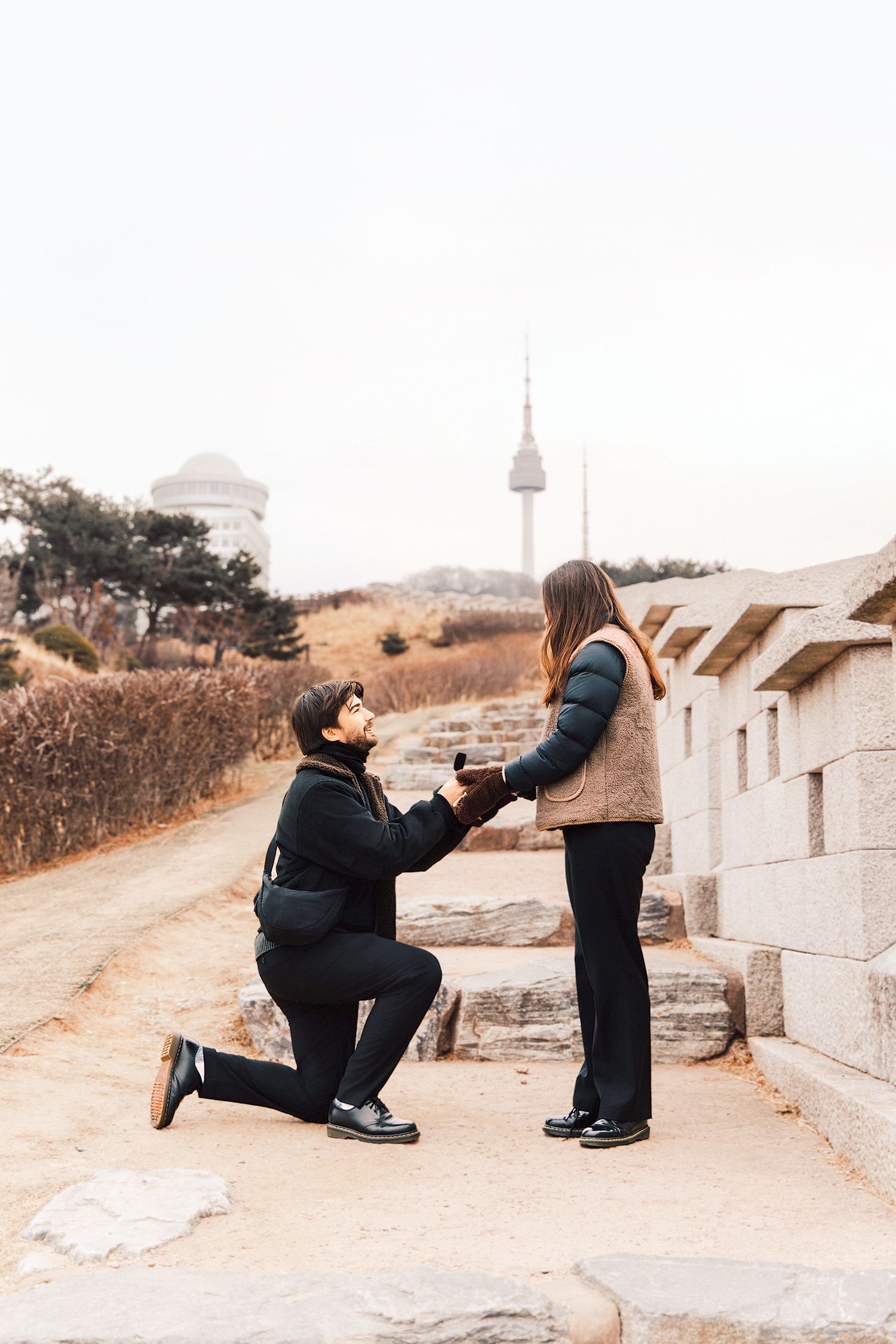 A sequence of photos showing a couple performing a playful dance move on stone steps in a park.