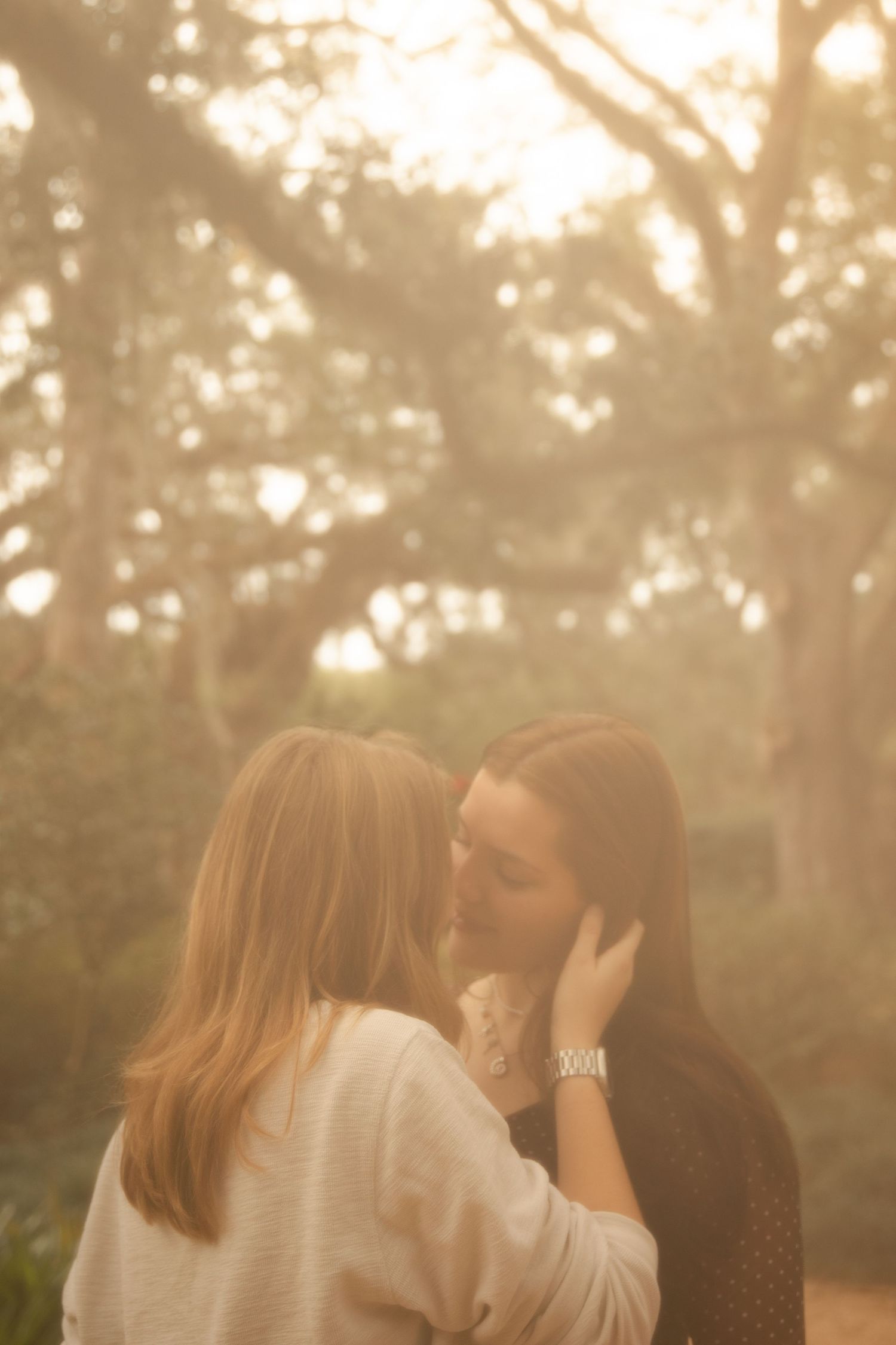 Two people sharing an intimate moment in a dreamy sunlit forest setting.
