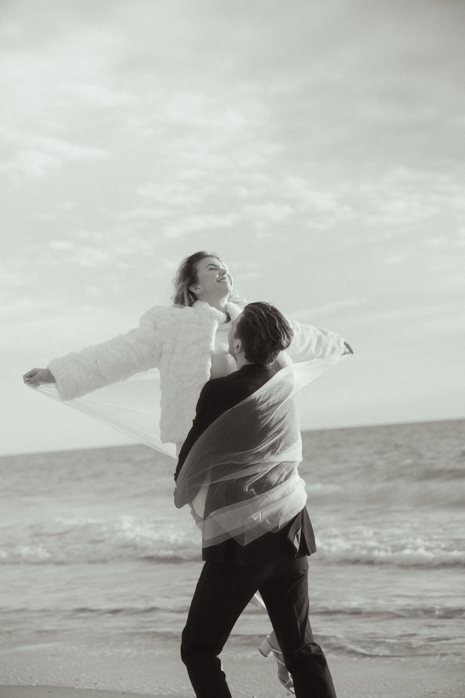 A sequence of black and white photos showing a person dancing freely on a beach with dramatic expressive movements.