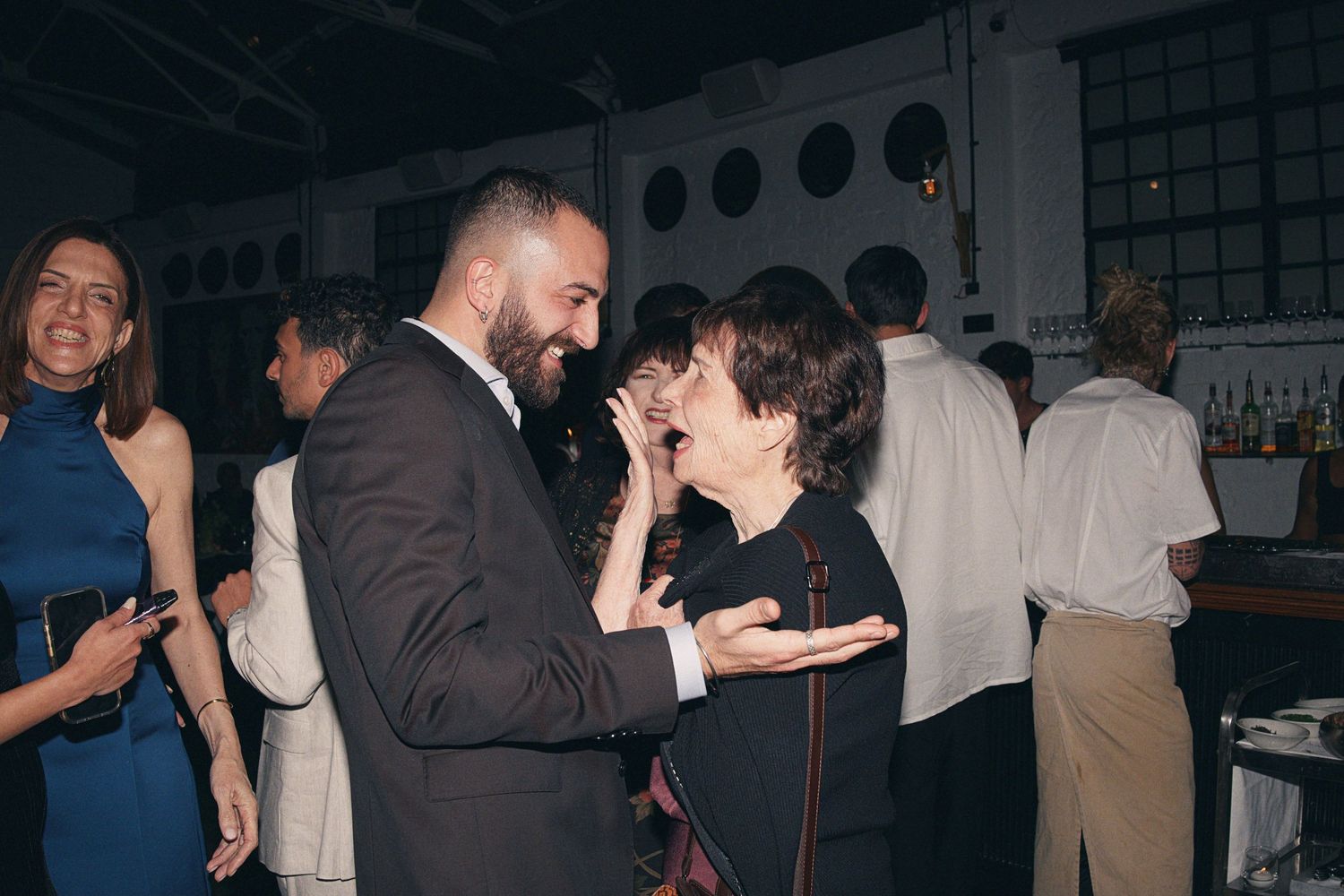 Two guests share a lively conversation at an elegant indoor social gathering or wedding reception.