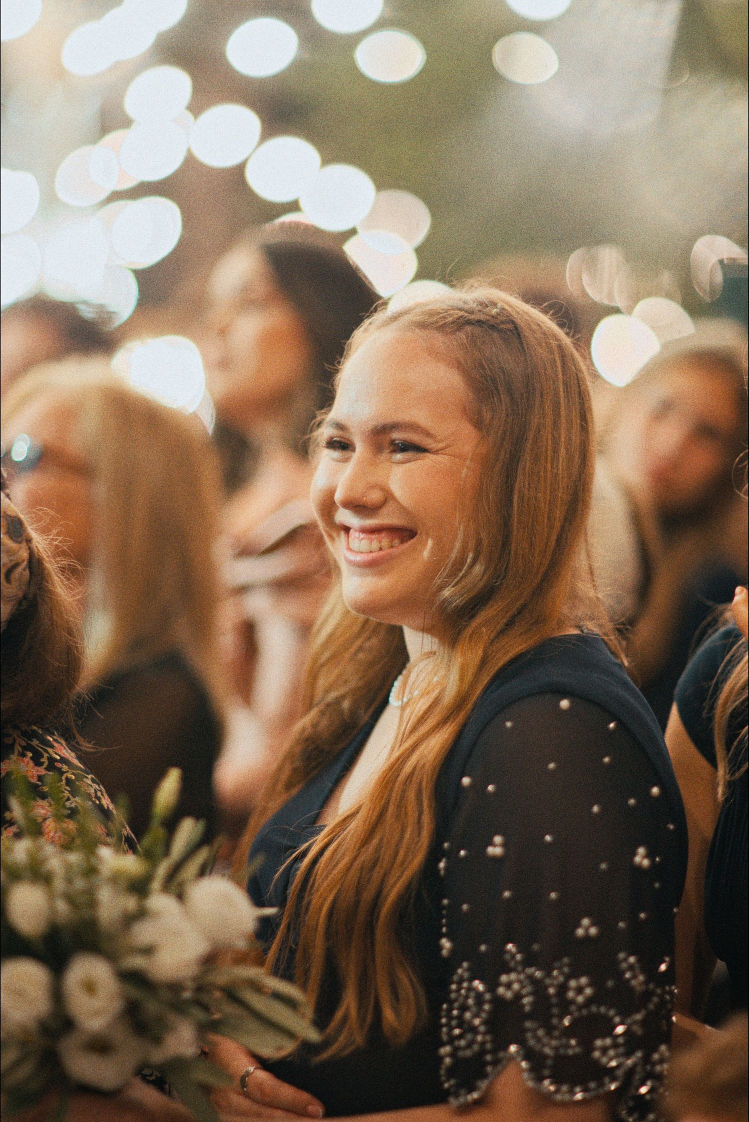 Wedding guests share joyful moments under soft bokeh lighting at an evening celebration.