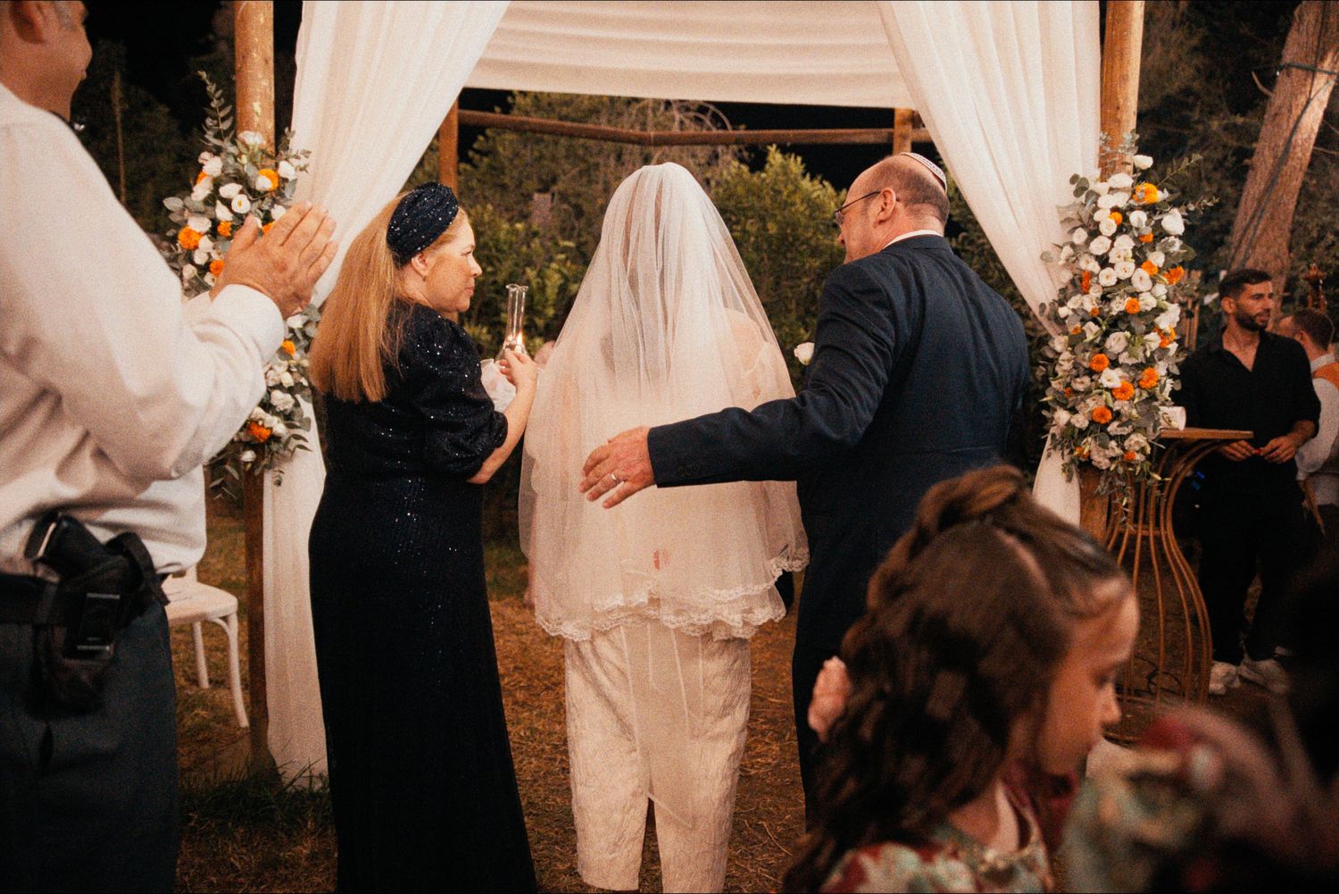 An outdoor wedding ceremony setup with white drapes and floral arrangements.