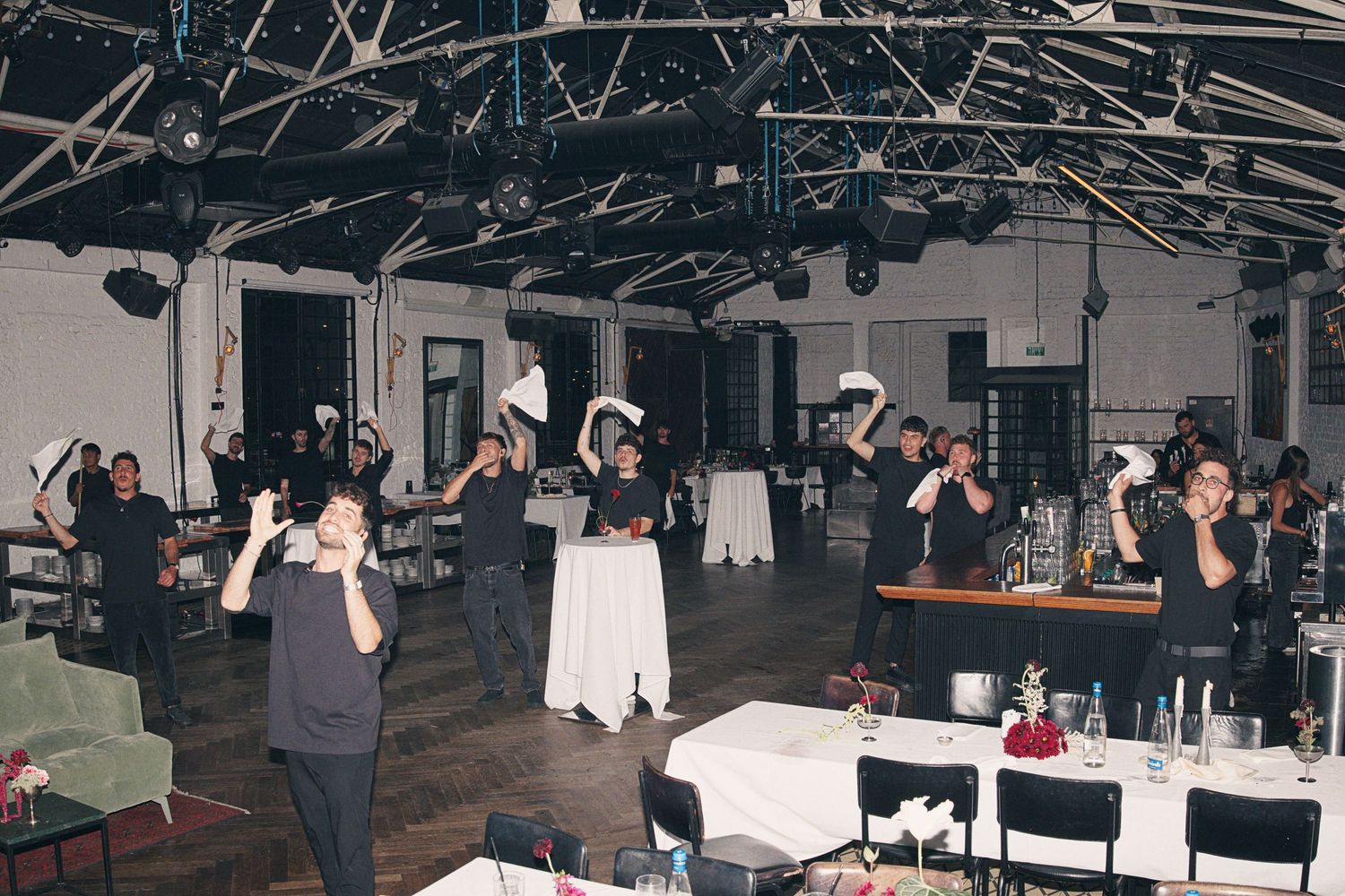Indoor event with guests and staff in black and white attire dancing and celebrating in a decorated banquet hall.