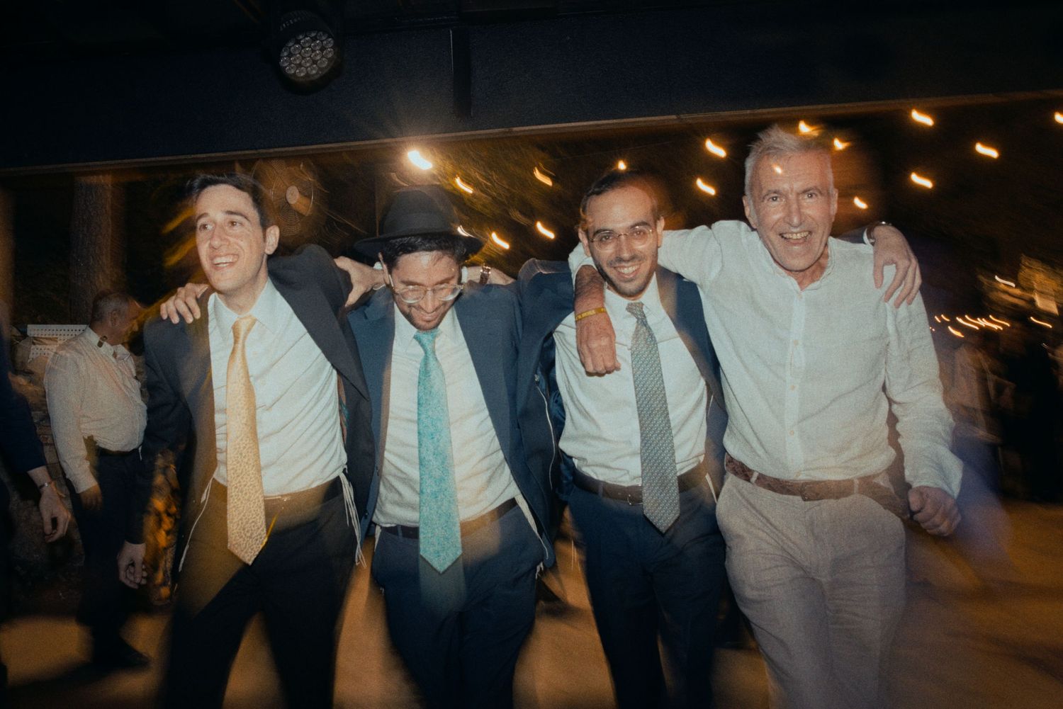 Group of friends in formal wear dancing and laughing together at an evening celebration.