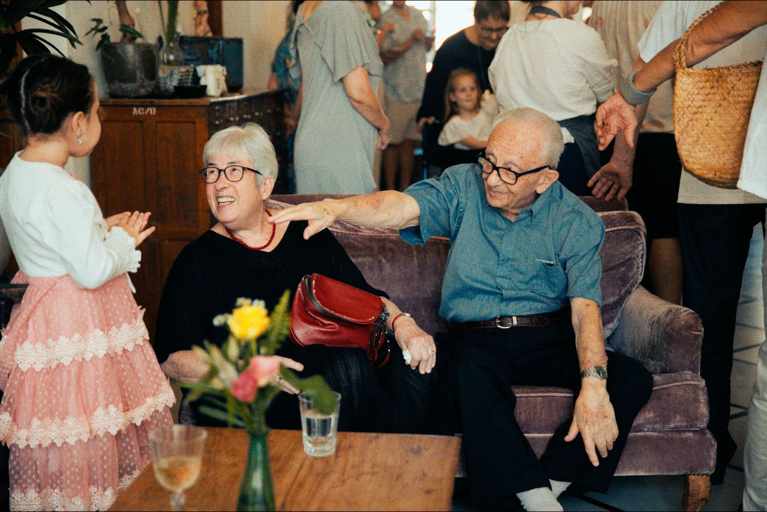 Elderly guests interact with a young child at a social gathering.