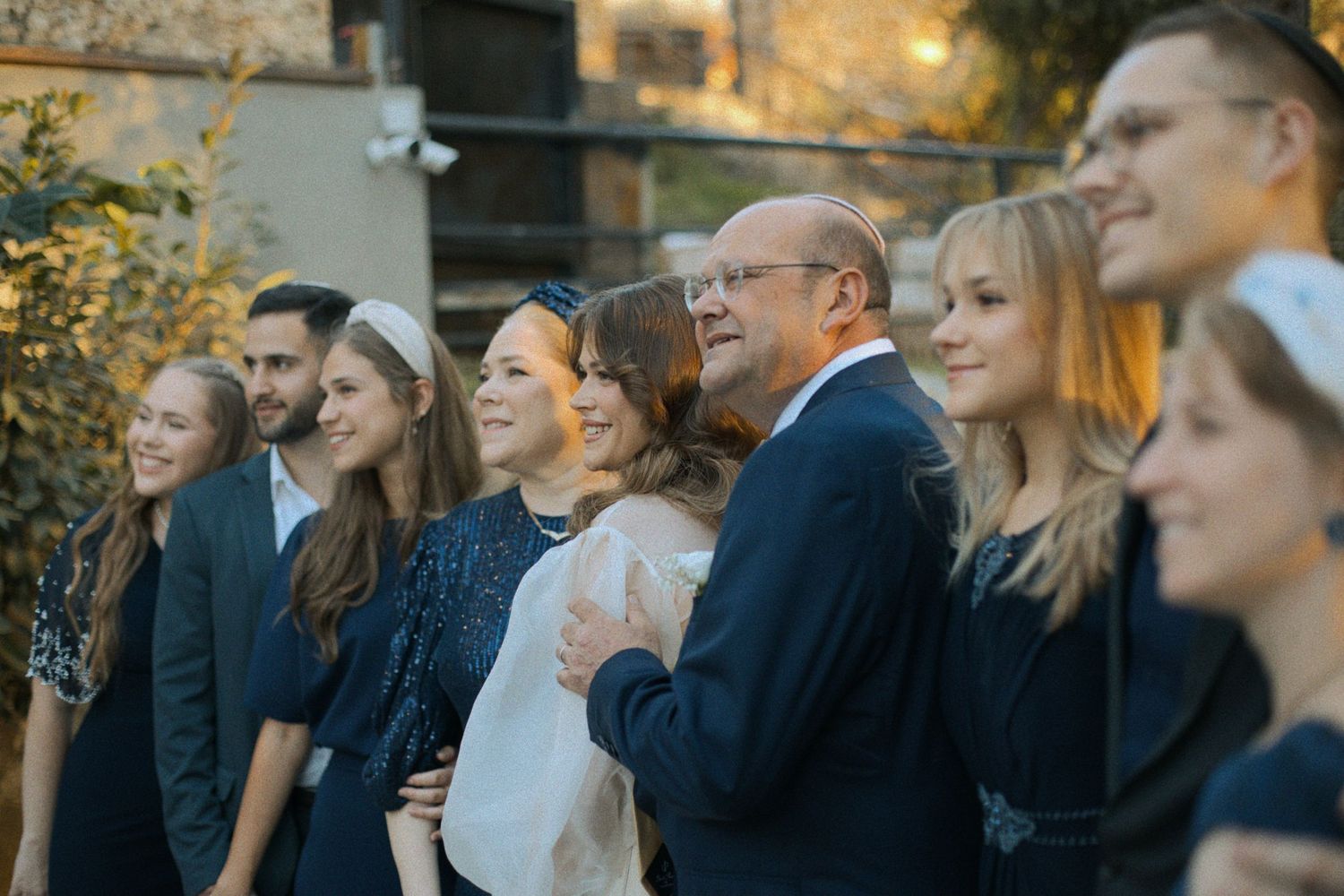 Wedding party members arranged in formal poses outdoors during golden hour.