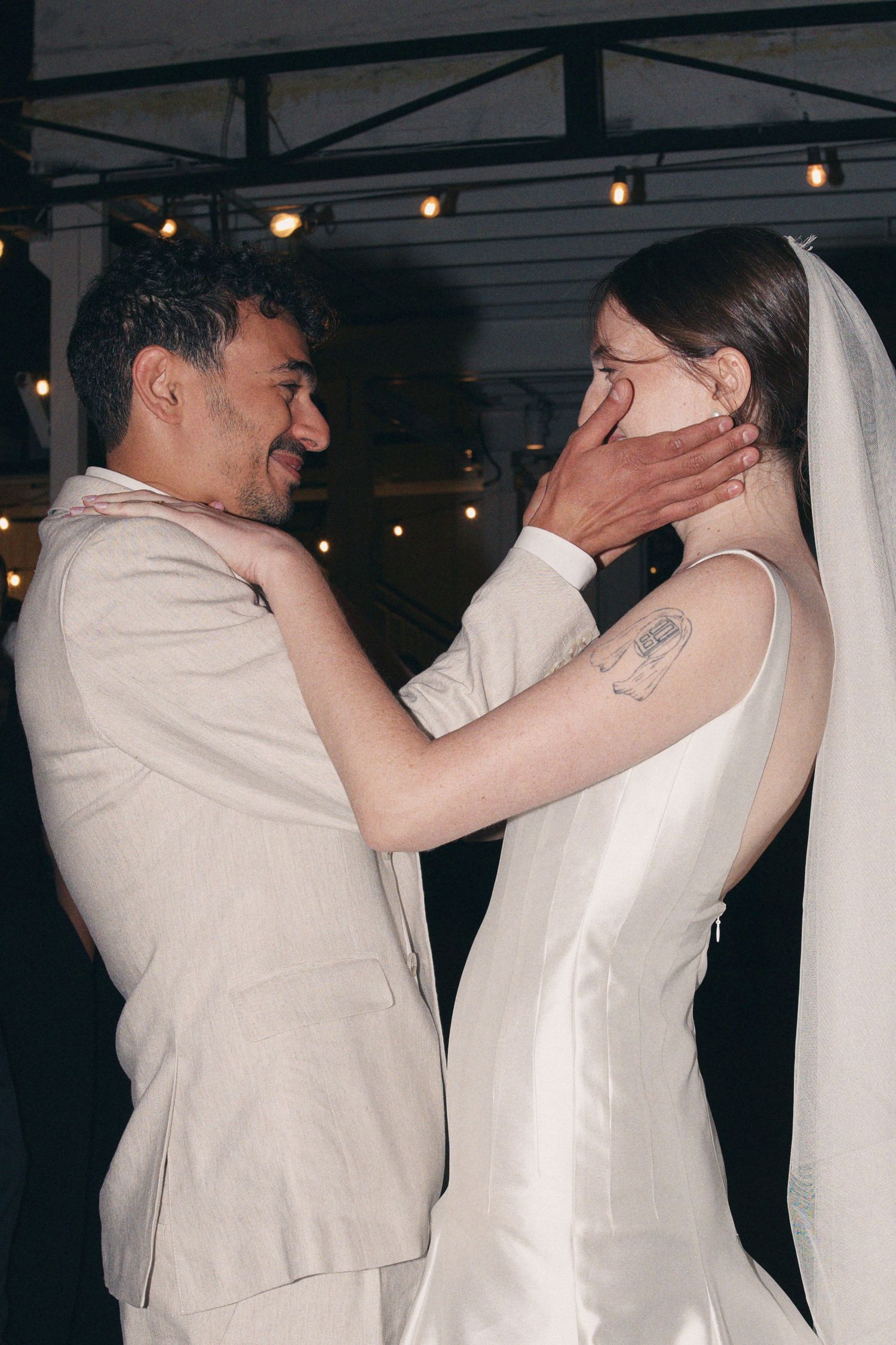 Bride and groom share an intimate first dance moment under warm string lights at their wedding reception.