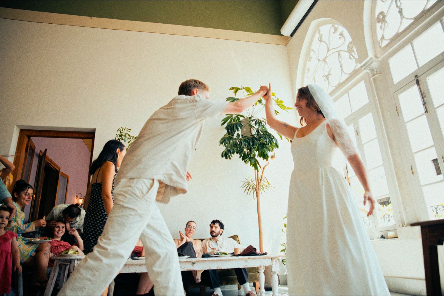 Wedding celebration in a bright white room with tall windows and decorative moldings.