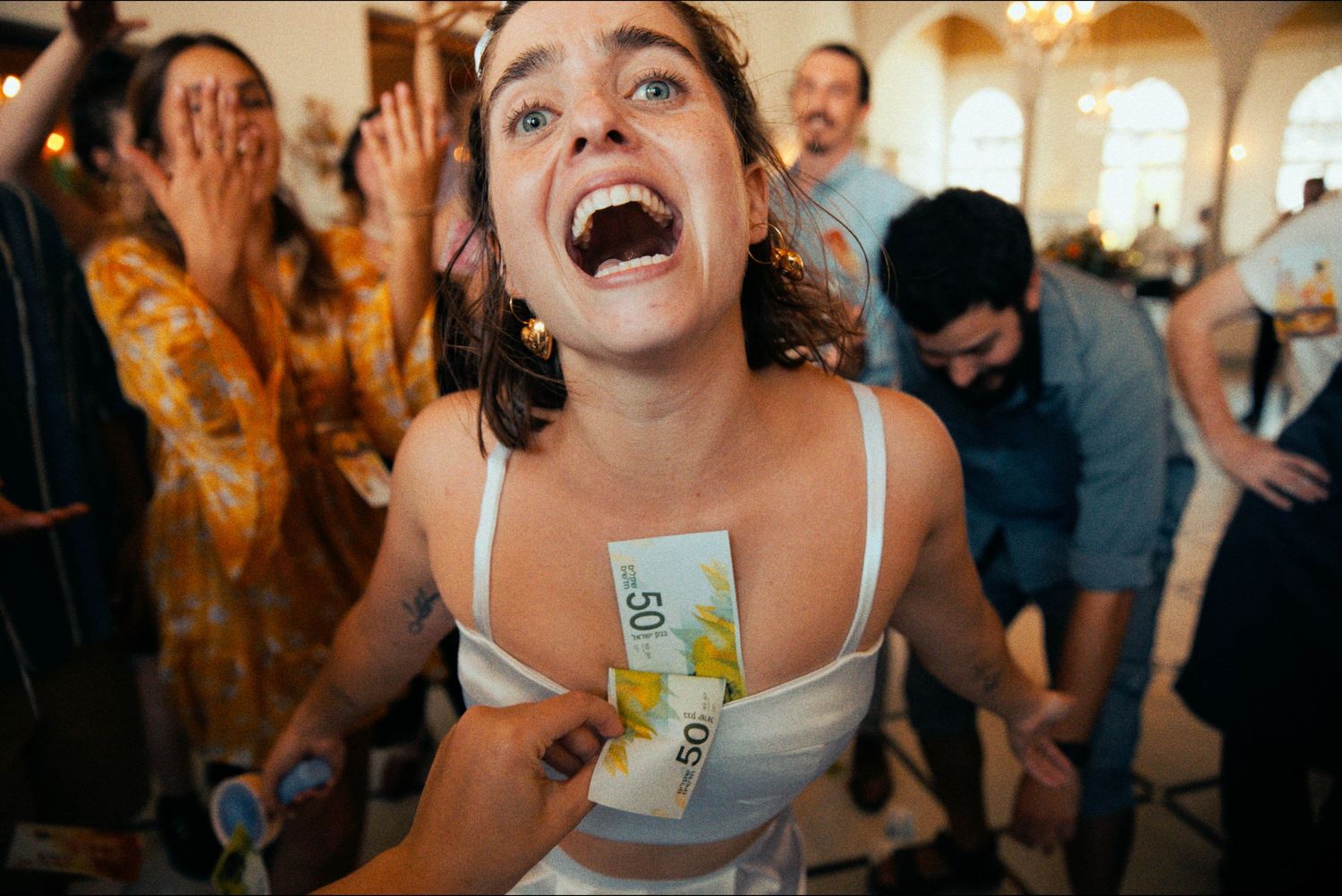 Joyful celebration with guests dancing and laughing at an indoor event.