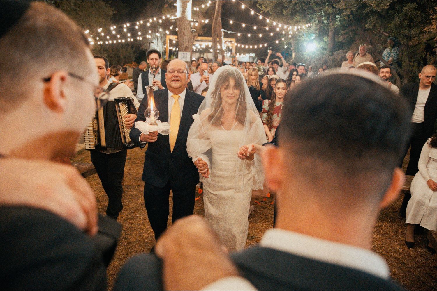 String lights illuminate an outdoor evening wedding celebration.