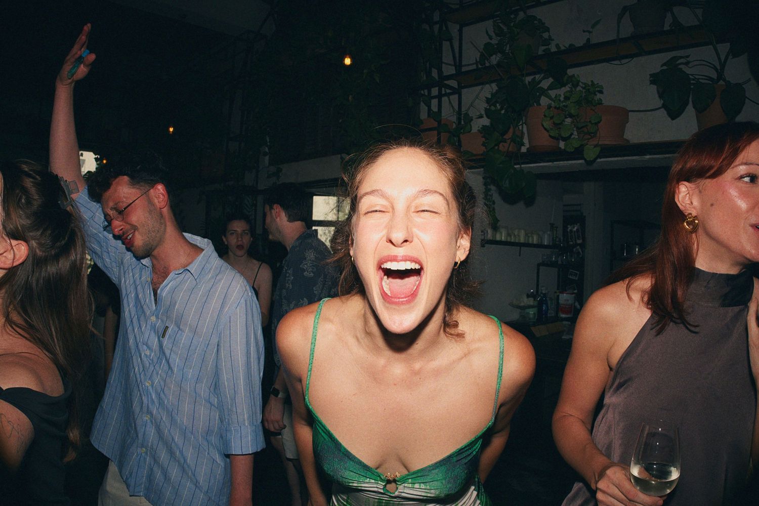 Joyful woman laughing and dancing at a lively indoor wedding reception party.