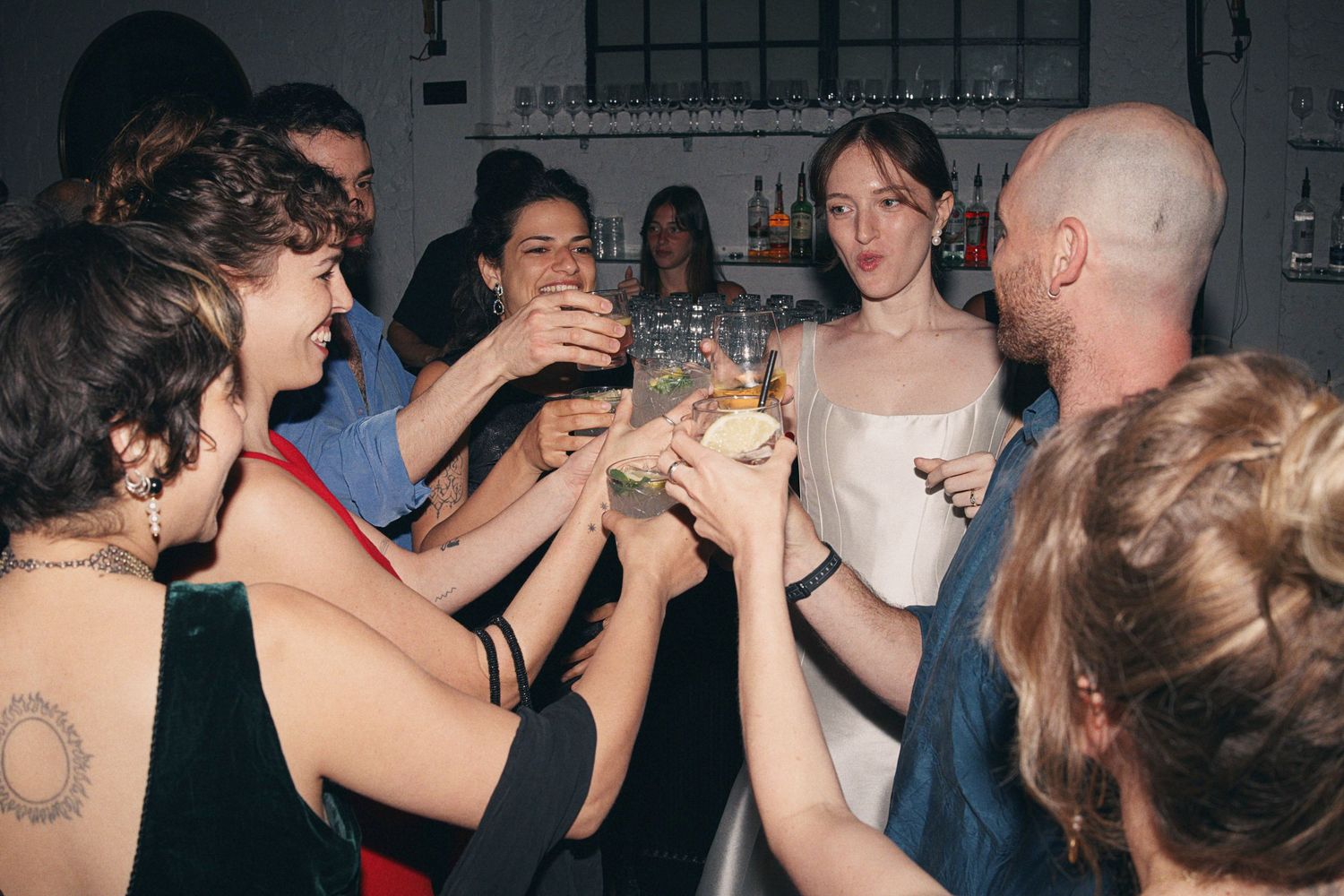 A group of people toasting with drinks at a lively party celebration indoors.