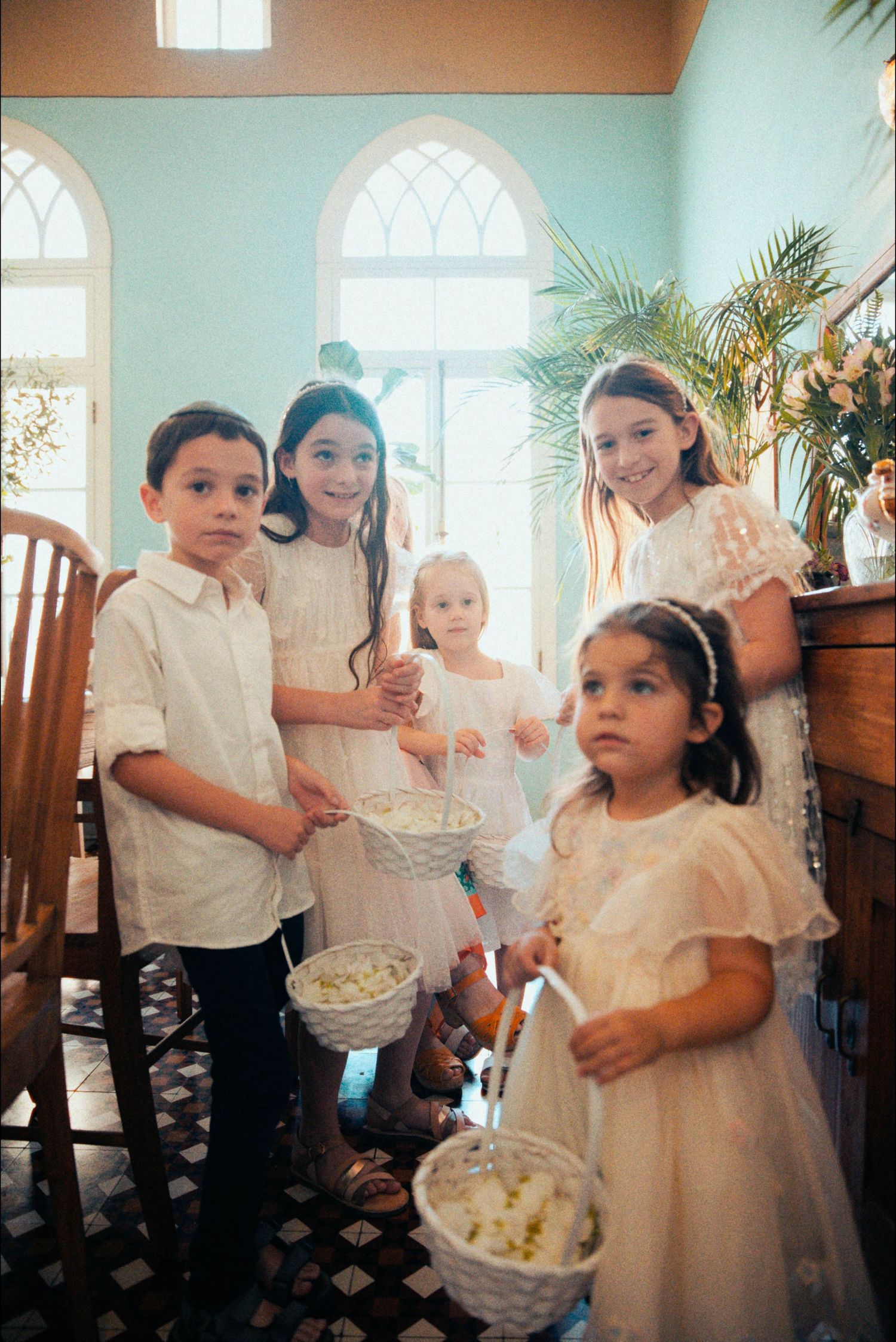 Children in white clothing gathered indoors during a special celebration.
