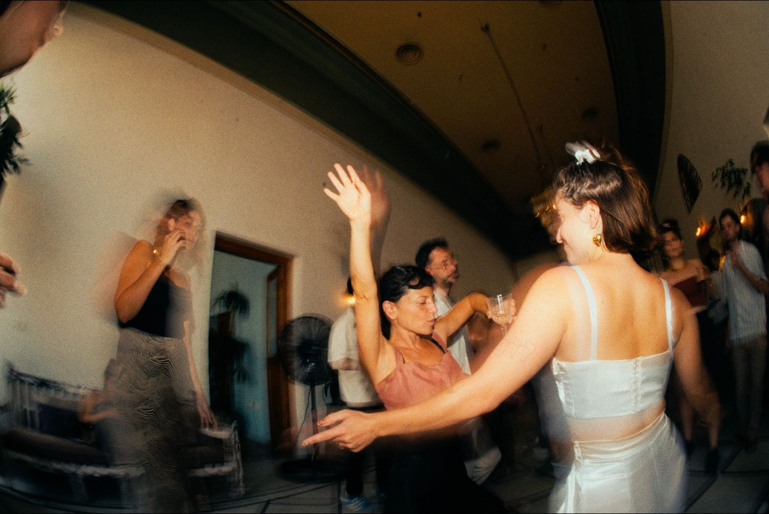 People dancing and moving energetically at an indoor celebration event.