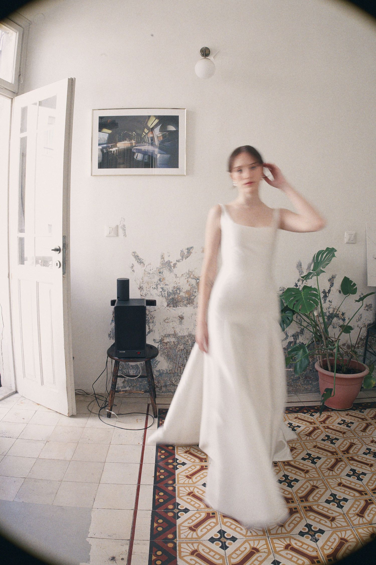 Bride wearing elegant white satin slip wedding dress standing in a vintage-tiled room.