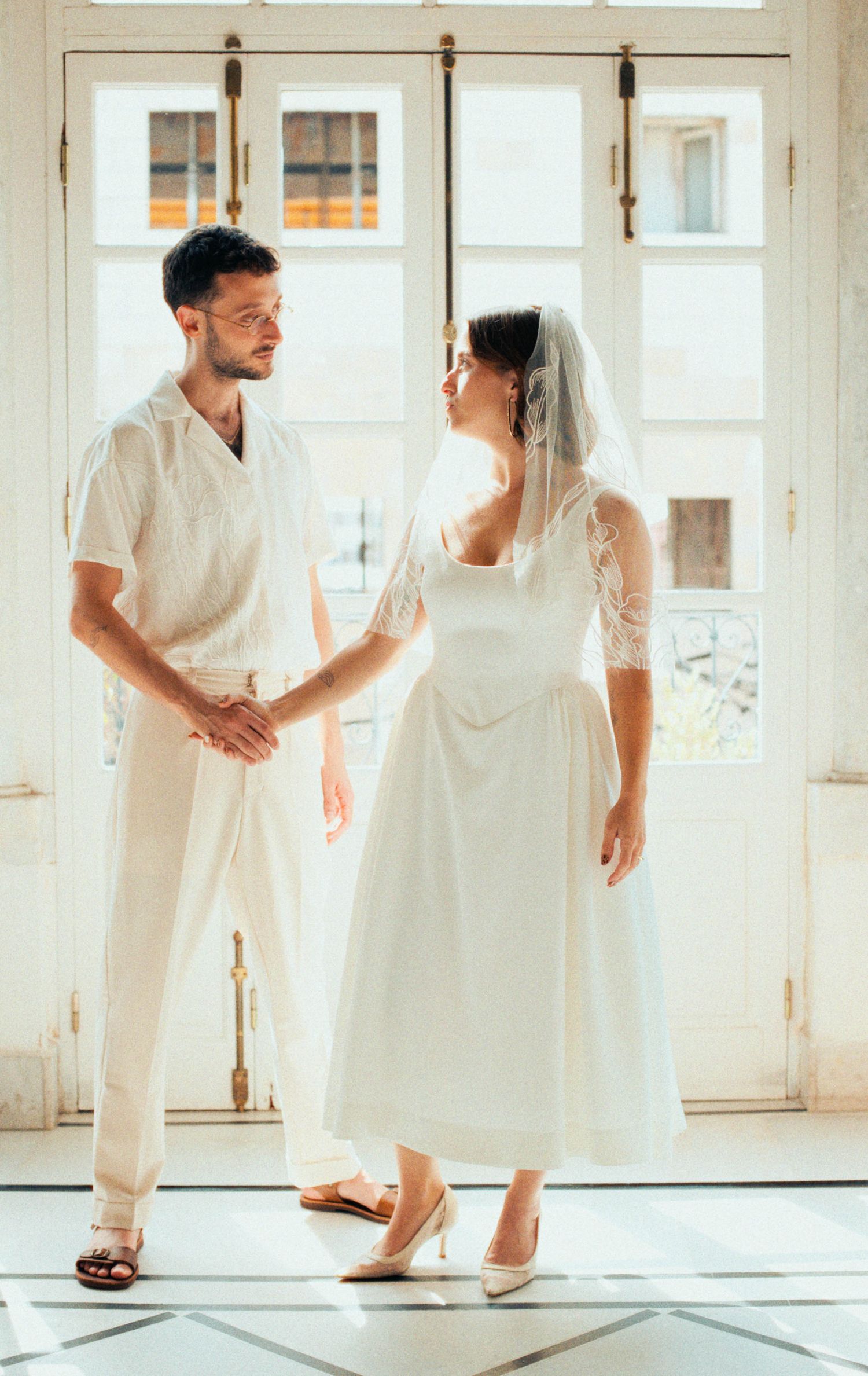 Playful wedding portraits in an all-white room showing natural interaction and movement.